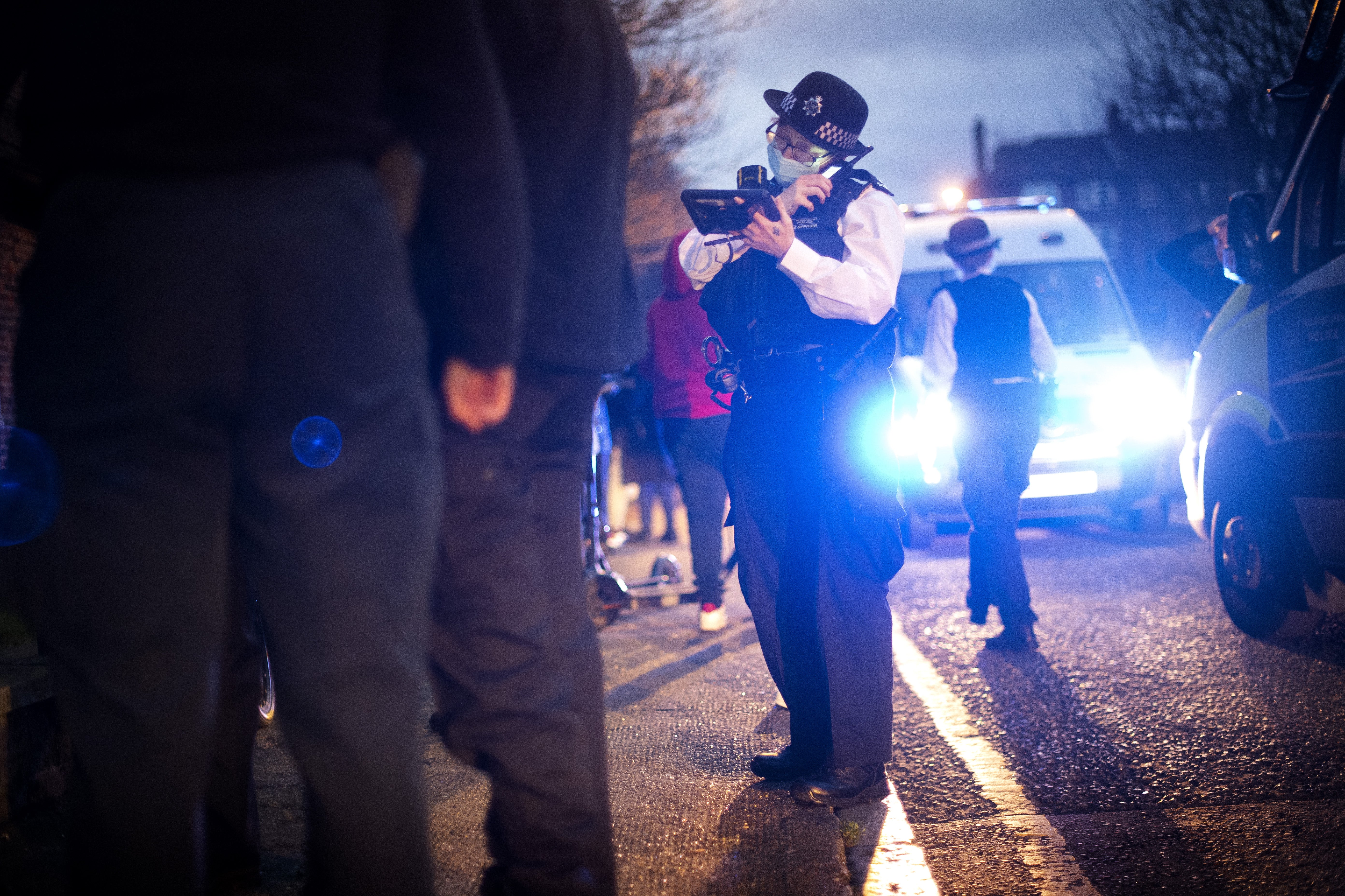 A female police officer uses her radio during a stop and search (Victoria Jones/PA)