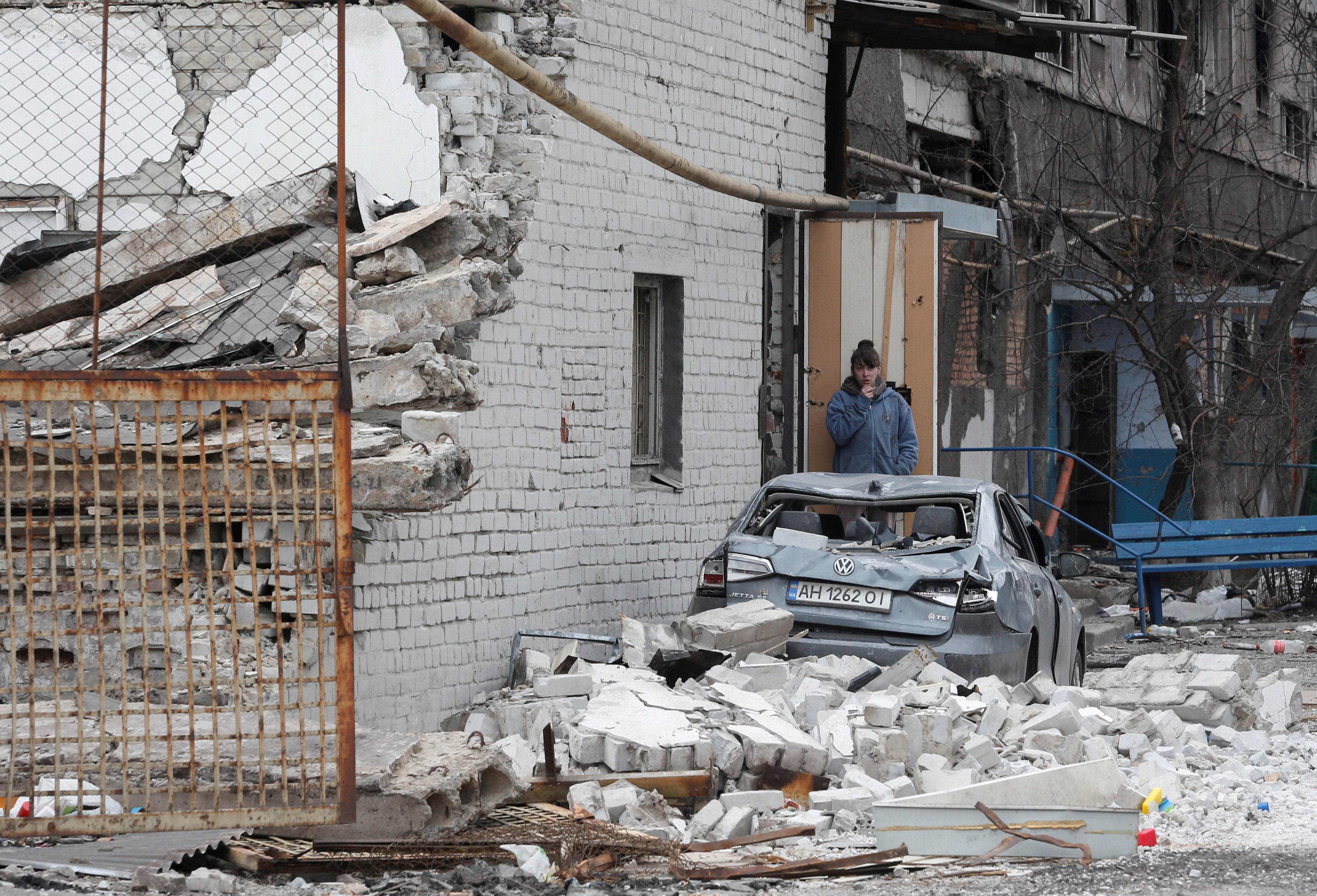 A local resident stands near an apartment building damaged by Russian airstrikes in the southern port city of Mariupol, Ukraine