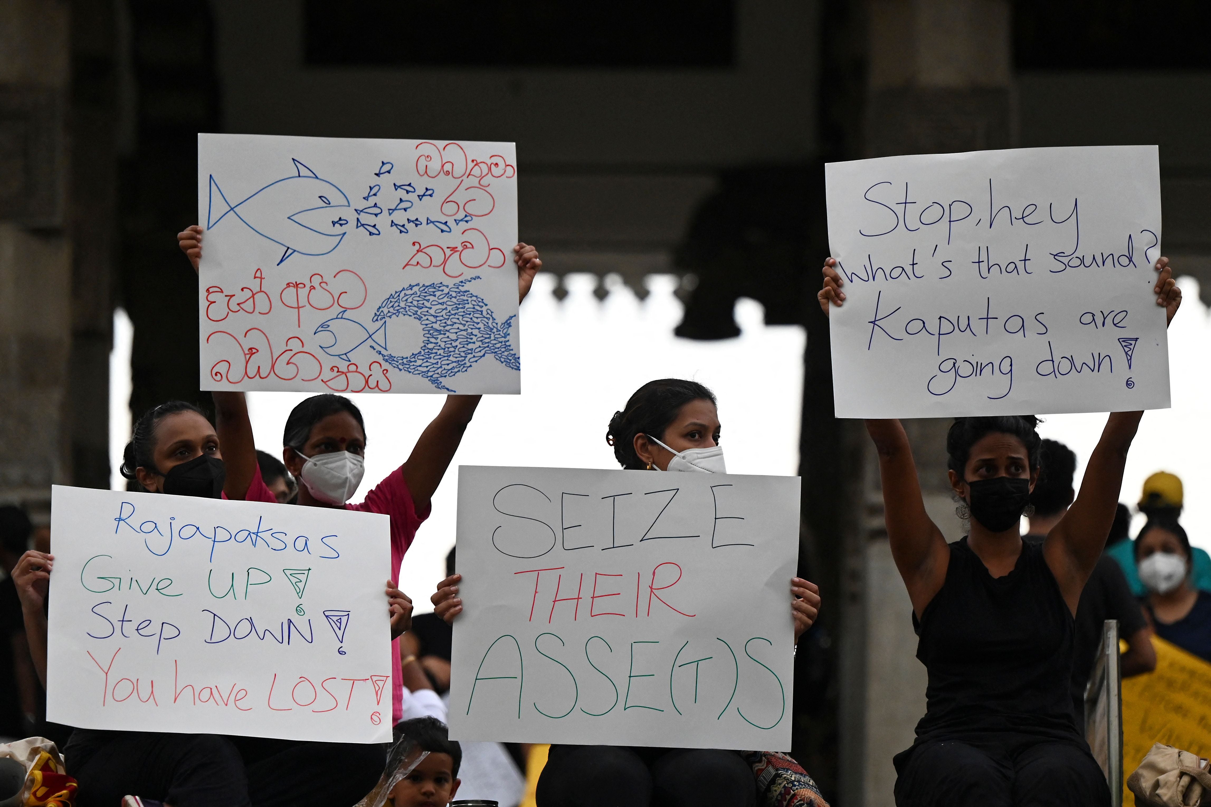 Protesters hold placards during a demonstration against the surge in prices and shortage of fuel and other essential commodities in Colombo