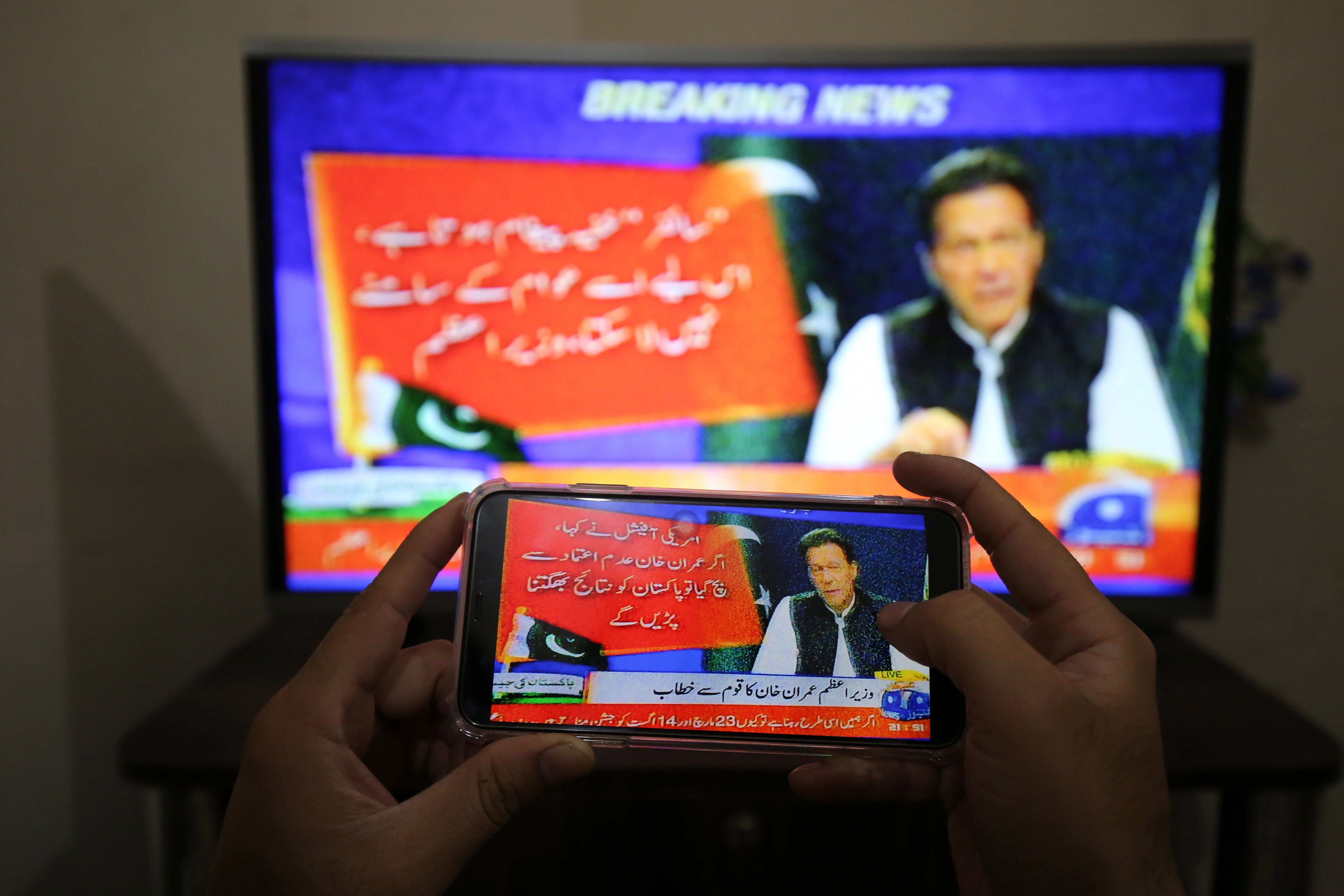 People watch a televised speech by the Pakistan Prime Minister Imran Khan, a day after the country's top court set aside the government's move to block a no-trust vote