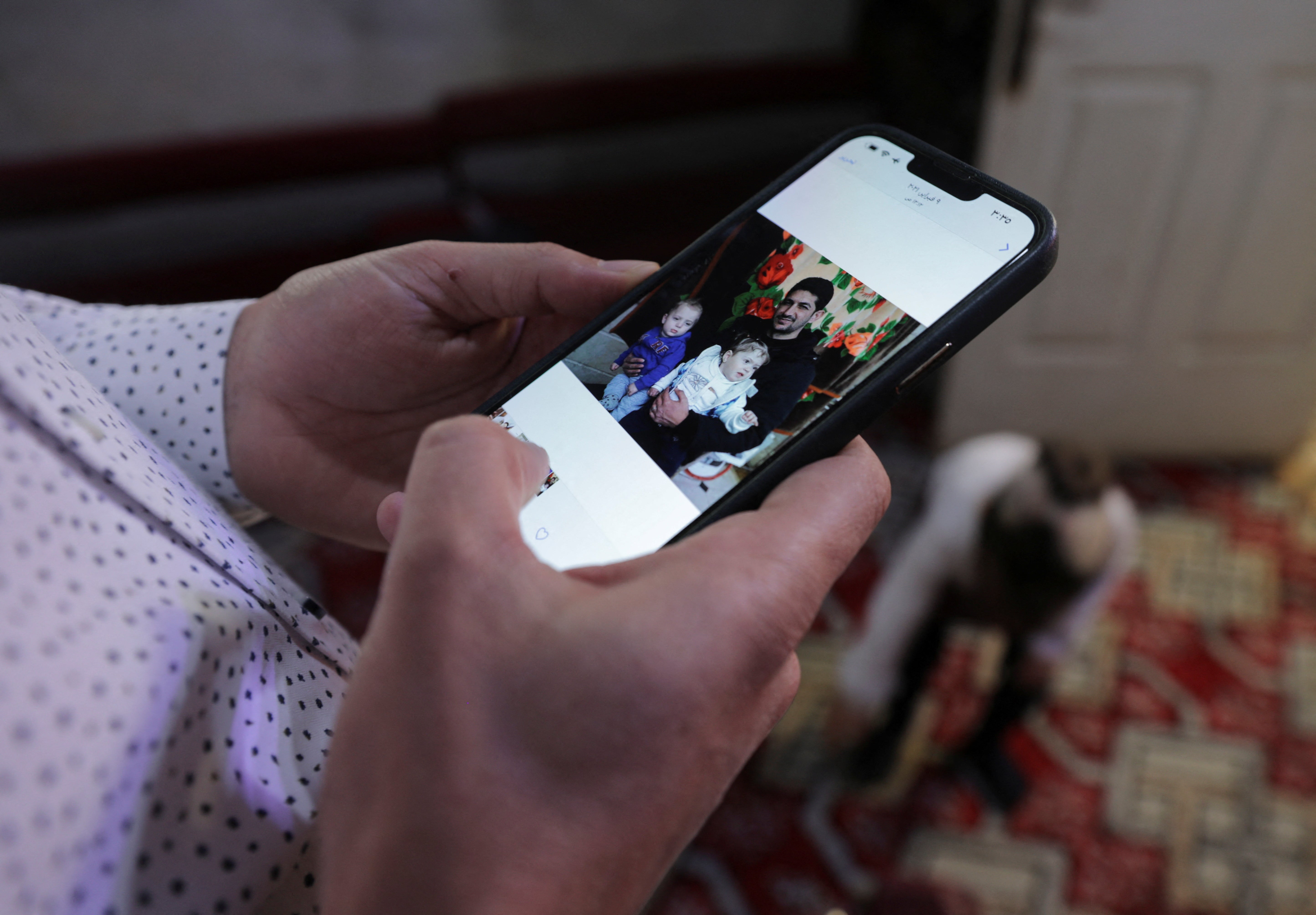 Abdel Hamid al-Youssef, shows a picture on his phone of his infant twins and his brother who he says were killed when poison gas was dropped on their home town