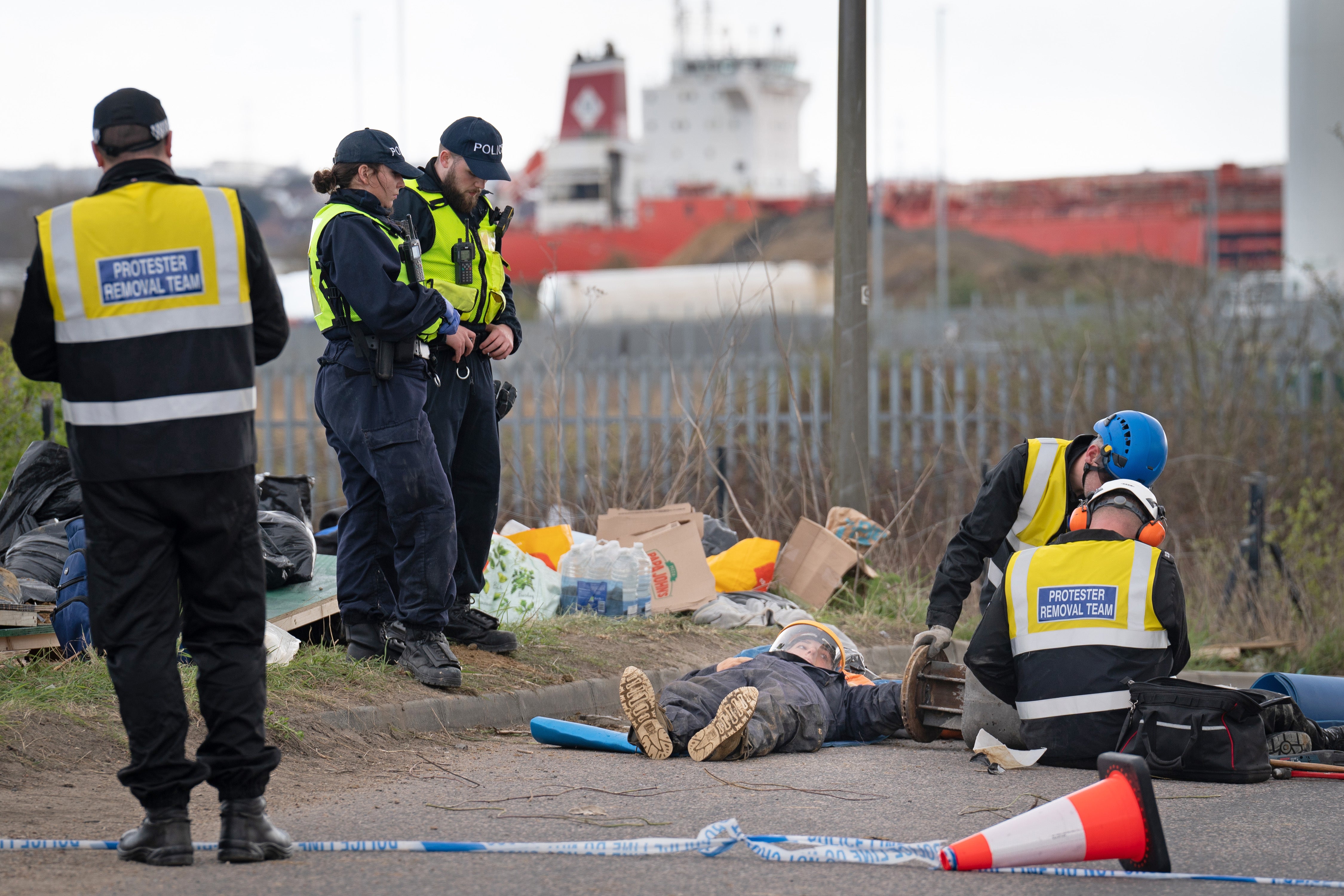 Police officers from the Protester Removal Team work to free a Just Stop Oil activist