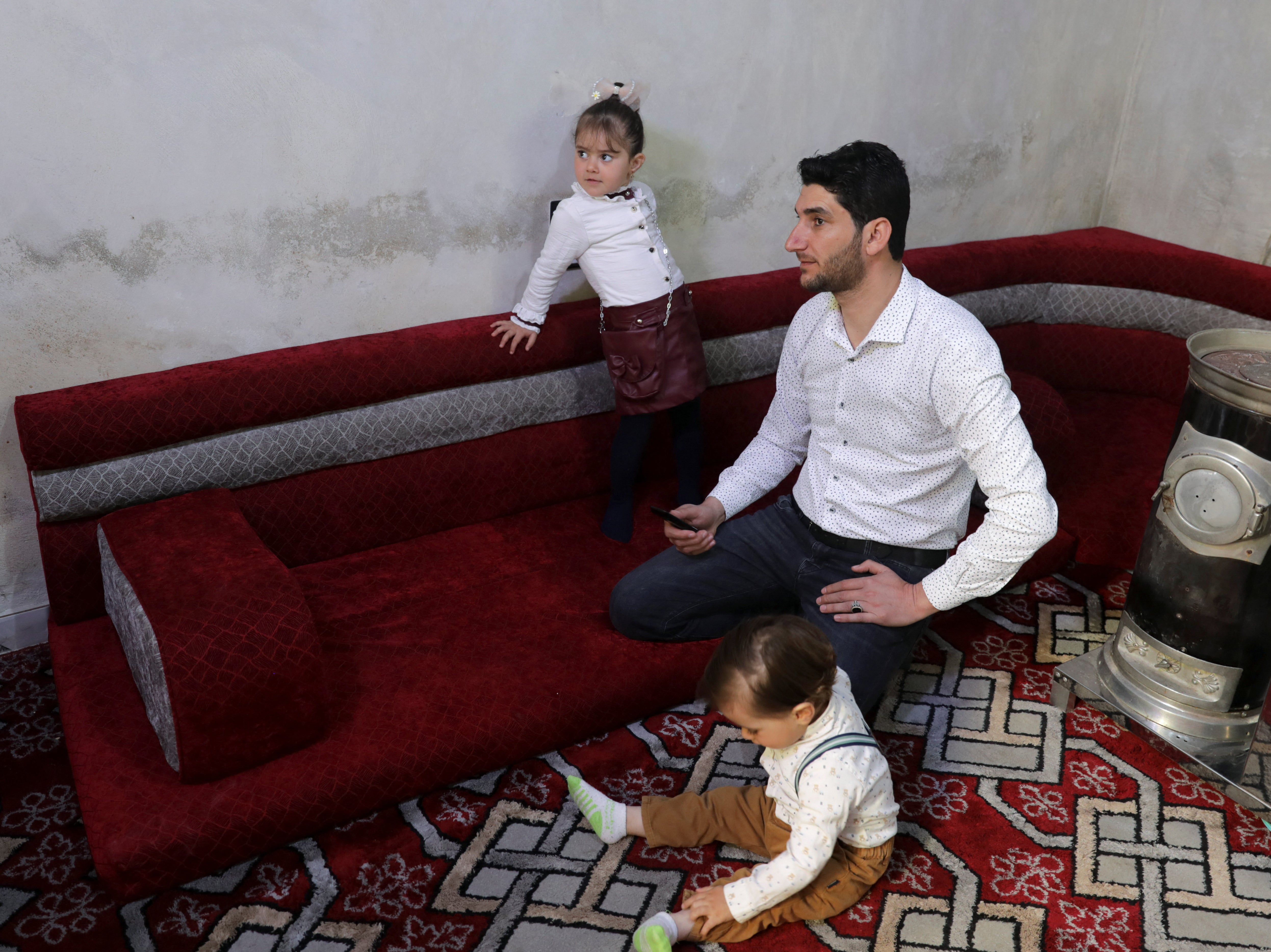 Abdel Hamid al-Youssef sits with his children at his home in the rebel-held town of Sarmada in Idlib province, Syria