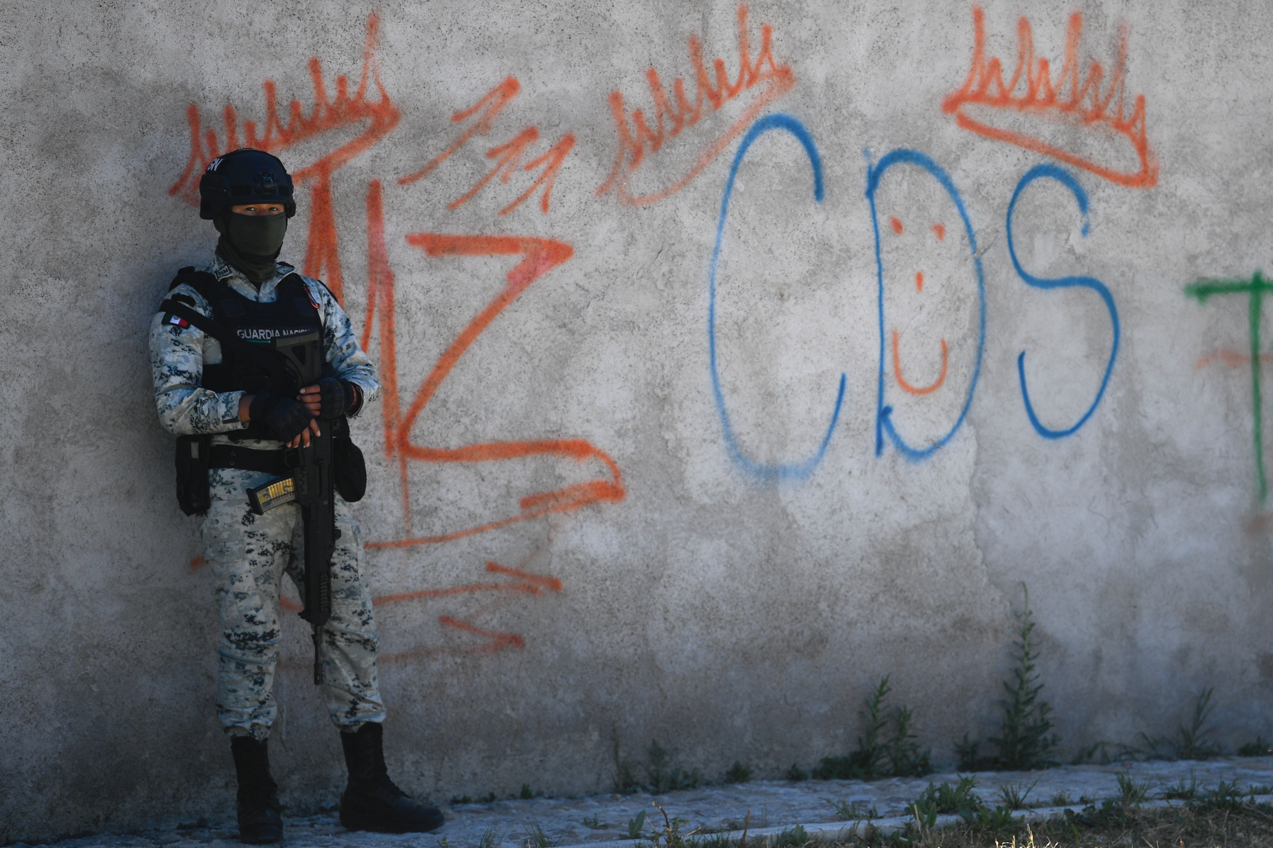 A Mexican soldier stands guard next to some graffitis of the drug trafficker Mayo Zambada (MZ) and the criminal group “Cartel de Sinaloa” (CDS), in Palmas Altas village, Jerez de Garcia Salinas municipality, Zacatecas state, Mexico