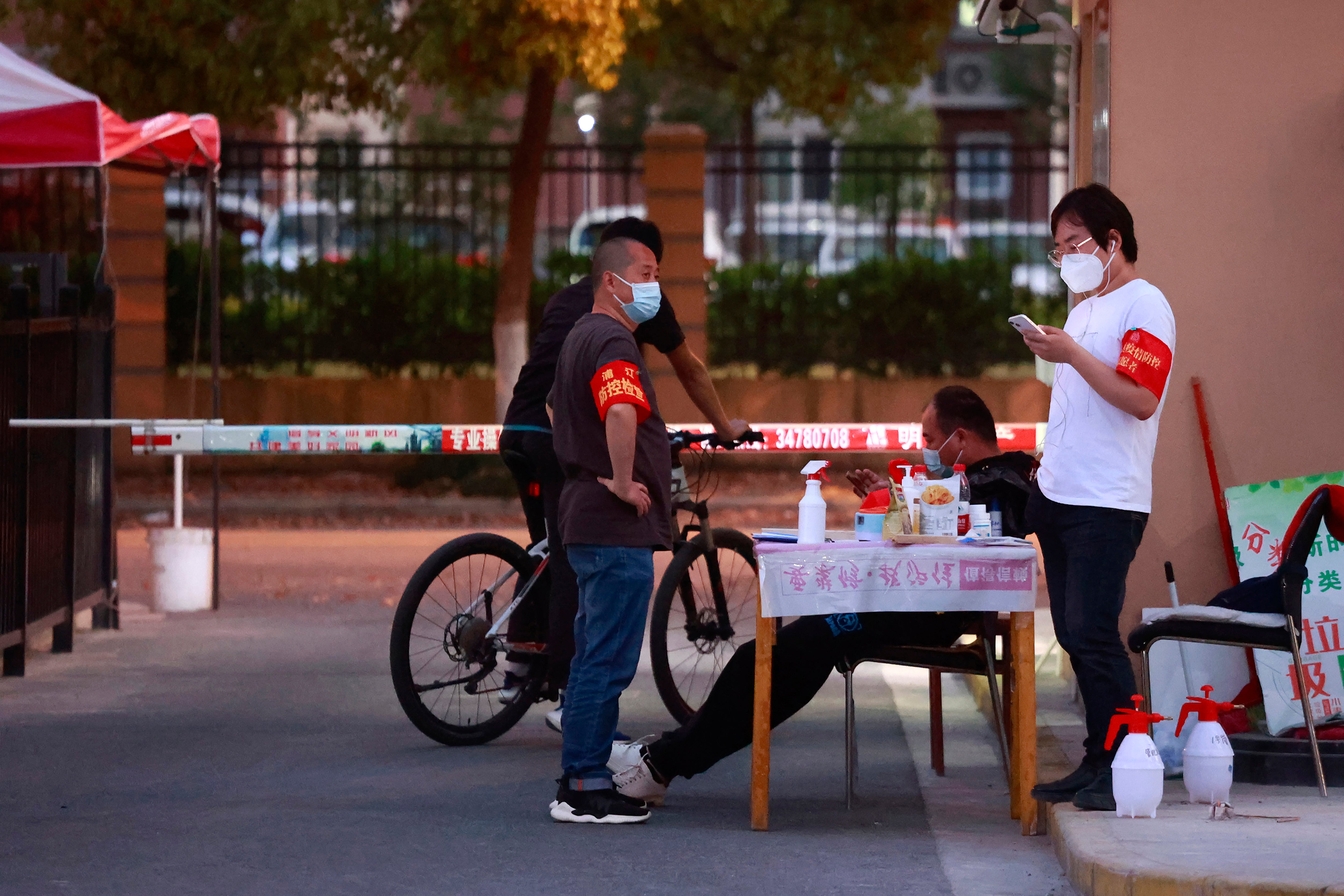 Volunteers wearing armbands and face masks stand at the gate of a residential community in Shanghai on 11 April