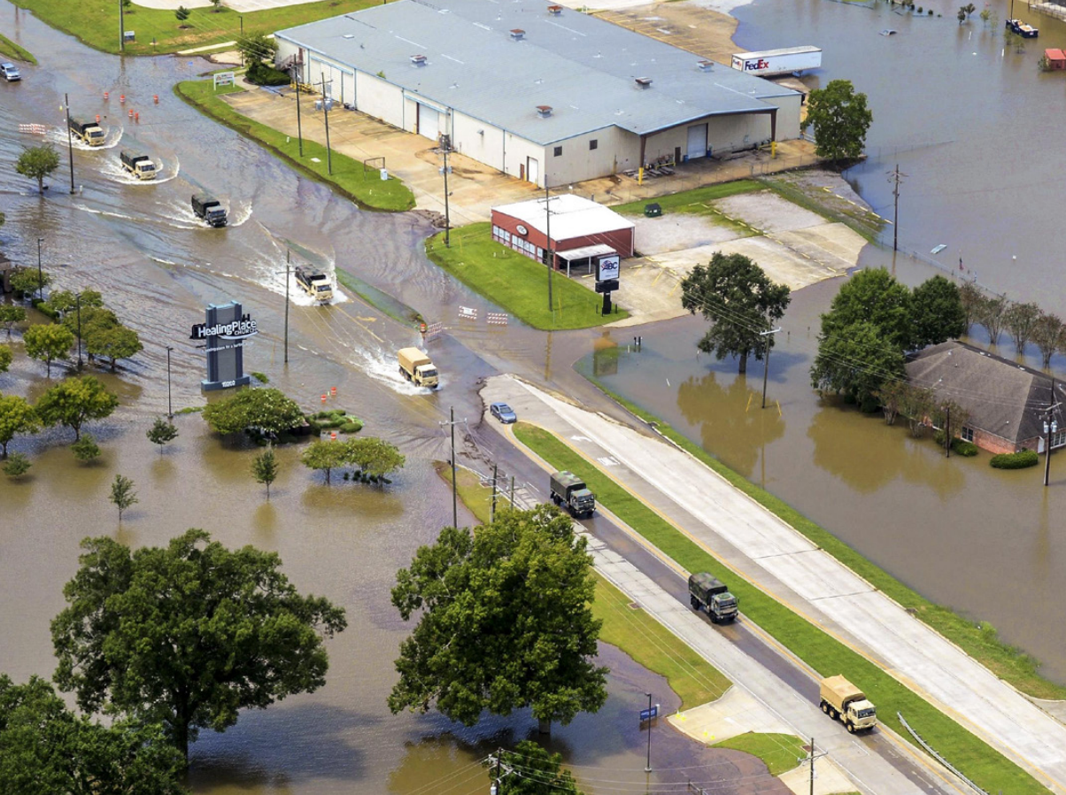 Army tactical vehicles transport flood relief supplies along a highway in Denham Springs, Louisiana after more than 30 inches of rainfall caused severe flooding in southeast portions of the state