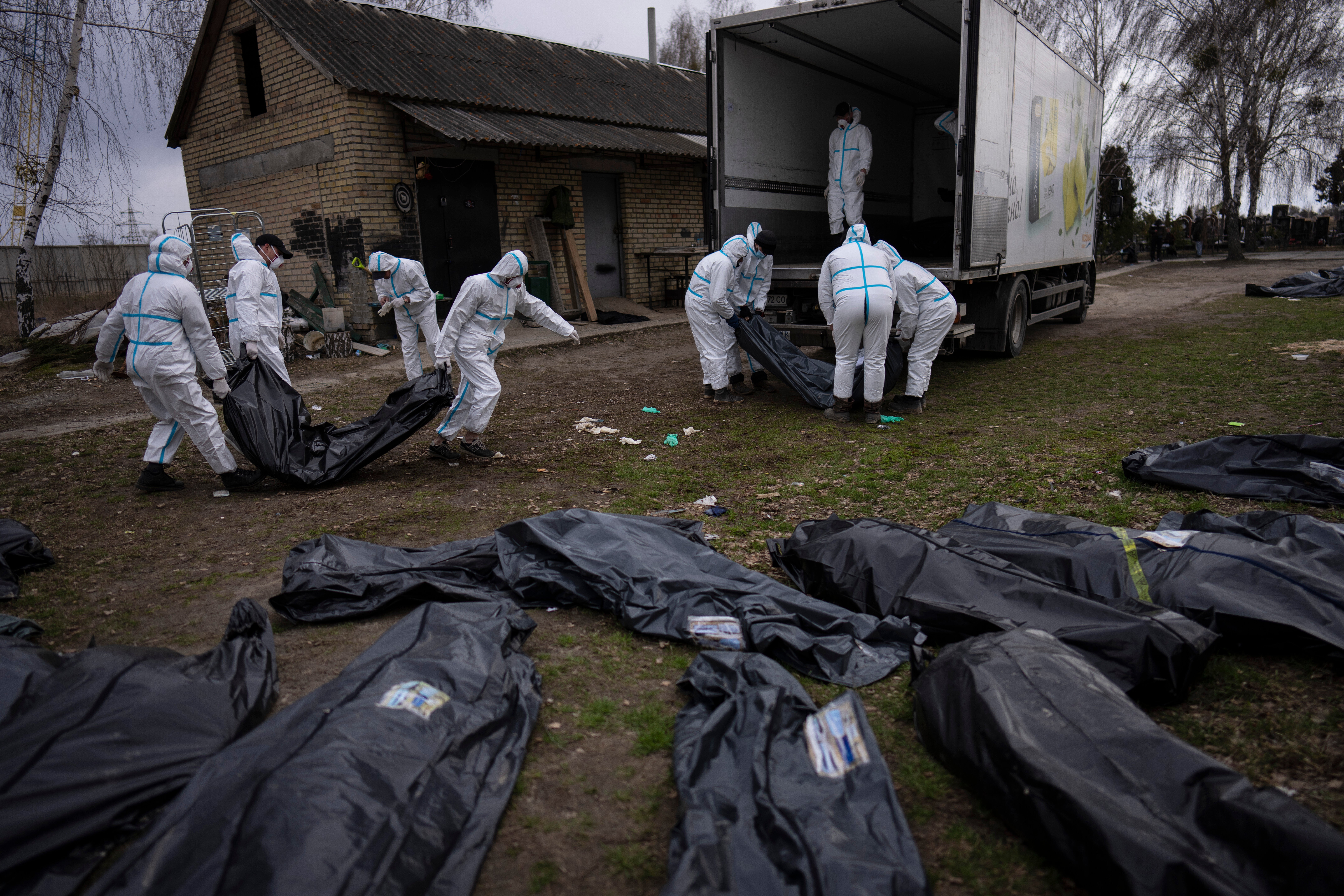 Volunteers load bodies of civilians killed in Bucha onto a truck to be taken to a morgue for investigation on 12 April, 2022