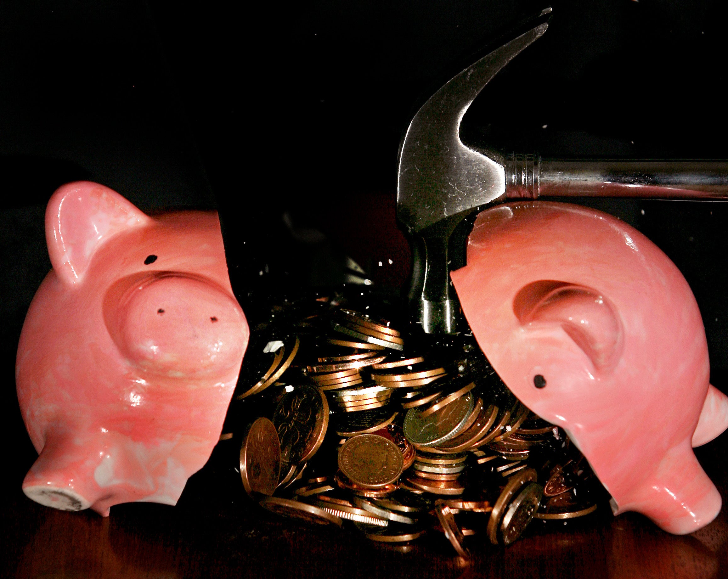 A traditional piggy bank is smashed open with a hammer.