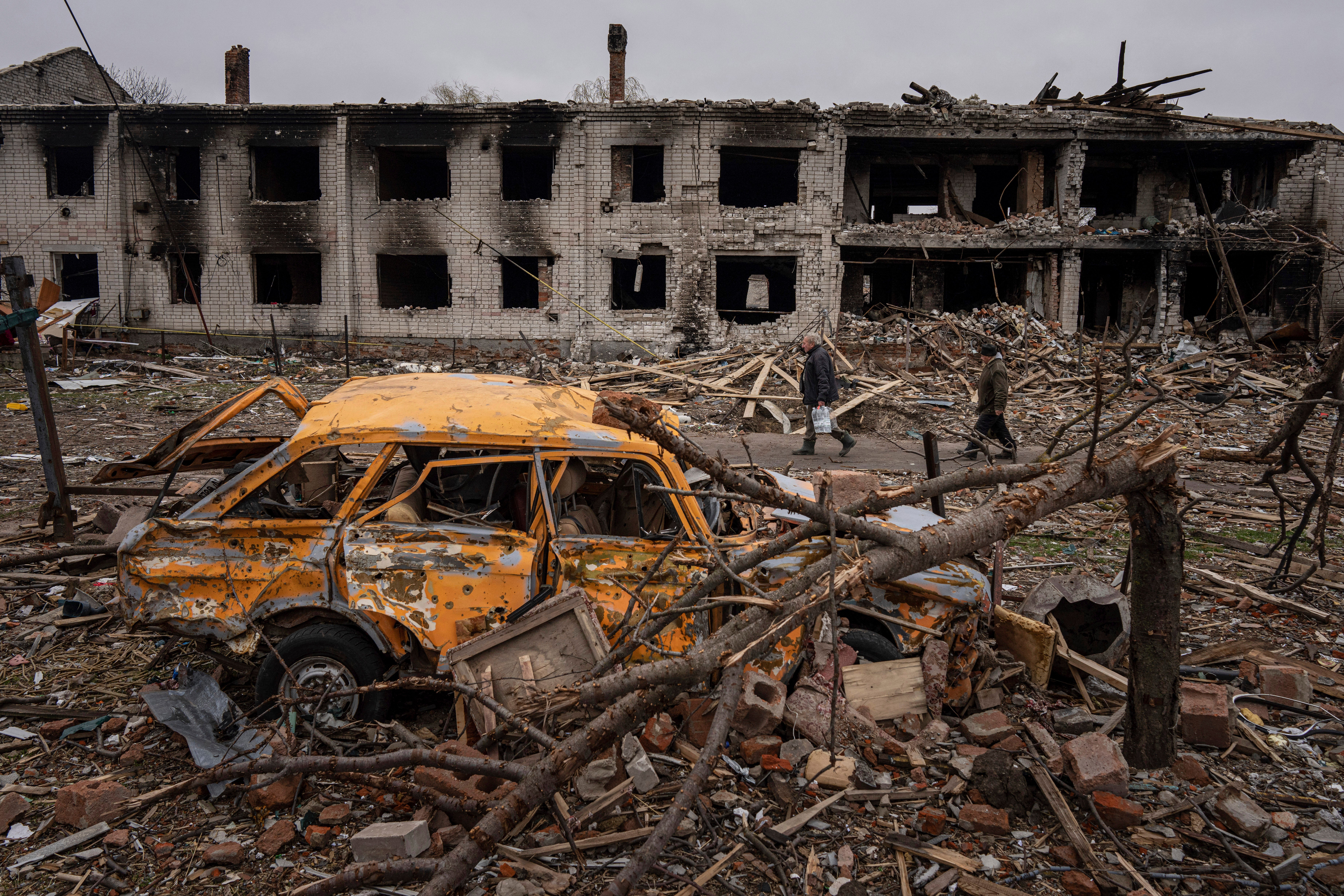 Men walk in a street destroyed by shellings in Chernihiv, Ukraine, Wednesday, April 13, 2022. (AP Photo/Evgeniy Maloletka)