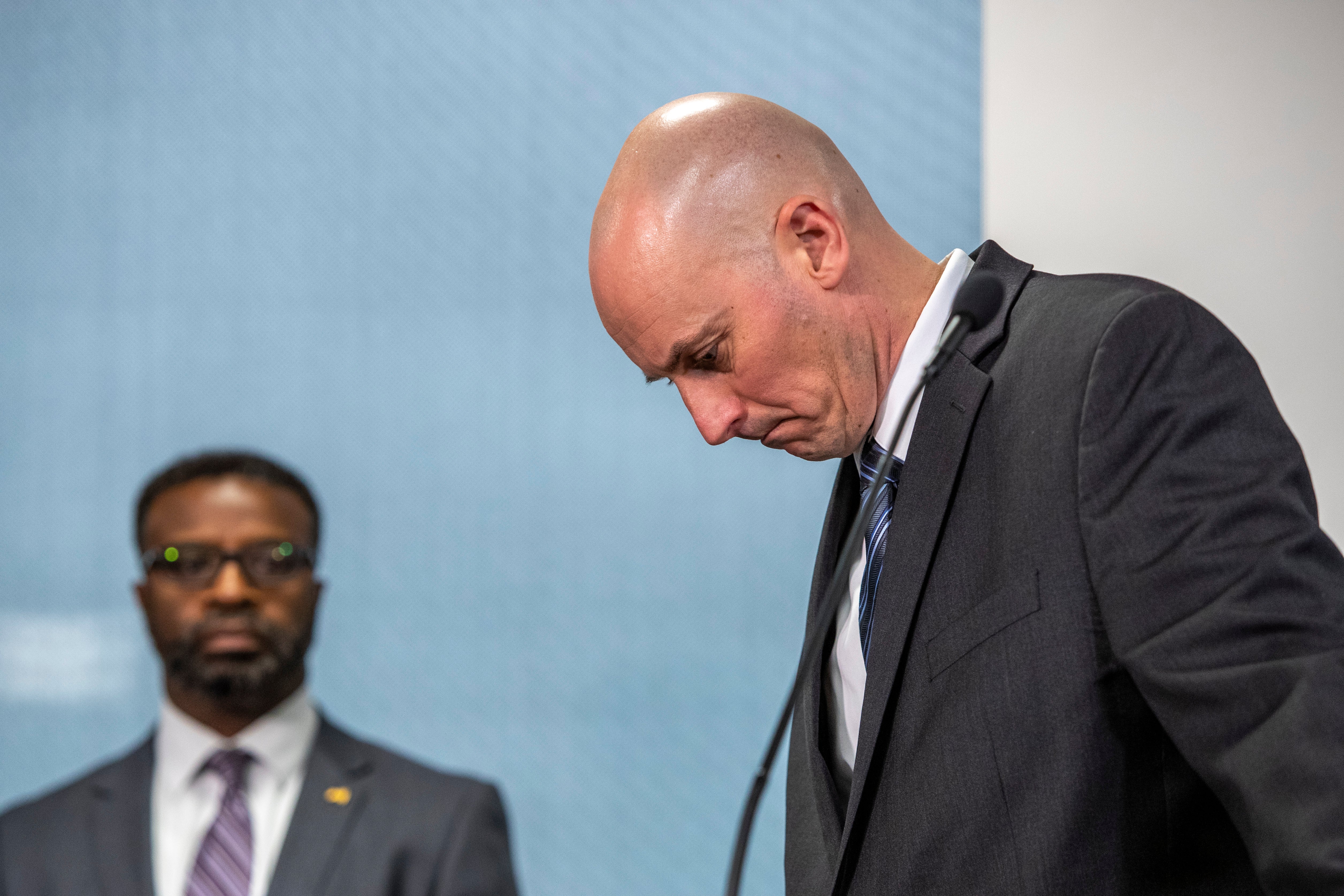 Grand Rapids Police Chief Eric Winstrom, right, and Grand Rapids City Manager Mark Washington react as a TV display shows evidence