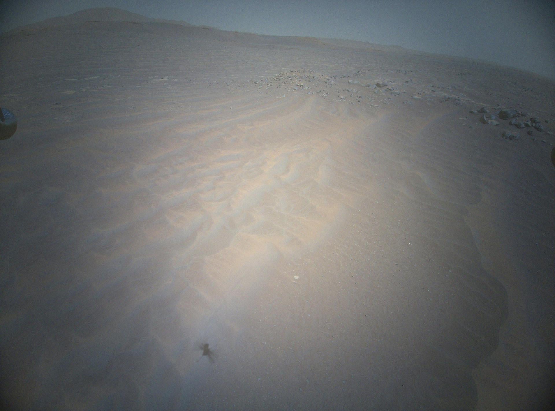 The shadow of Ingenuity, Nasa’s Mars helicopter, can be seen to the lower left as the vehicle soars above the Martian landscape