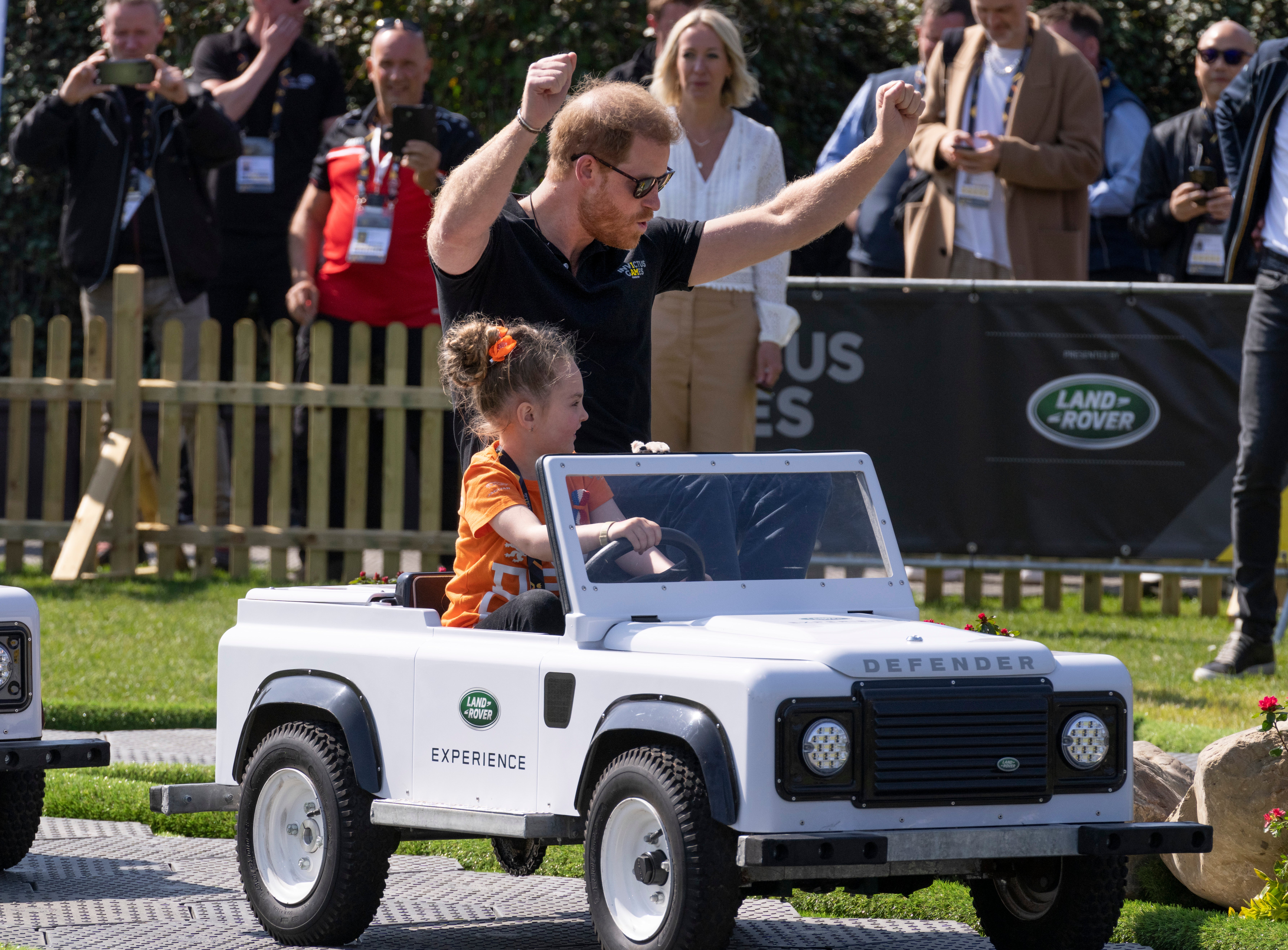 The Duke of Sussex celebrates when arriving first in a mini Land Rover driven by a child when attending the Land Rover Driving Challenge at the Invictus Games