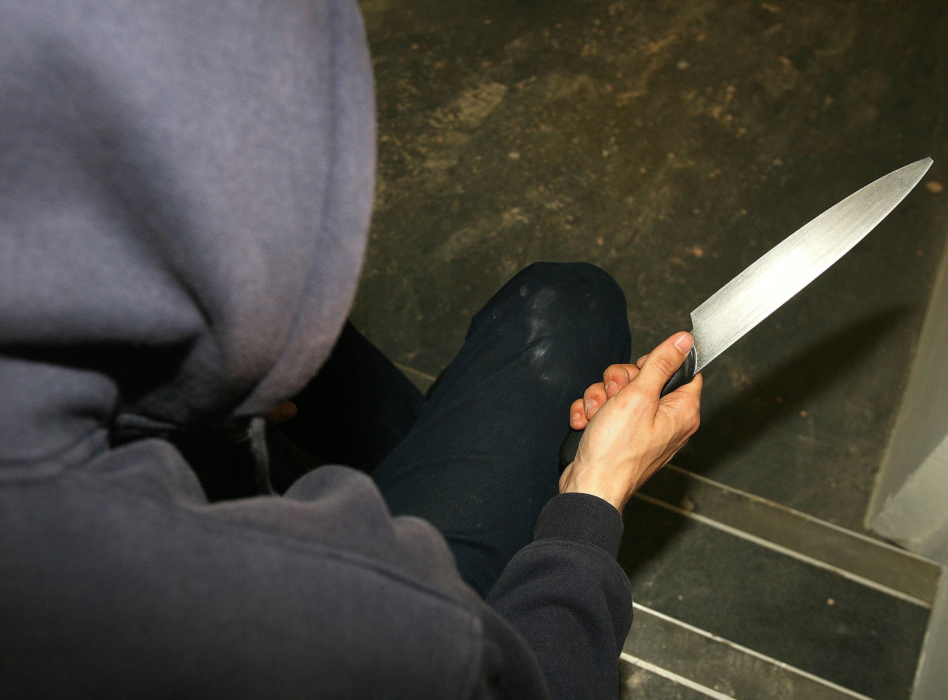 File photo of a man in a hoodie holding a knife. (Katie Collins/PA)