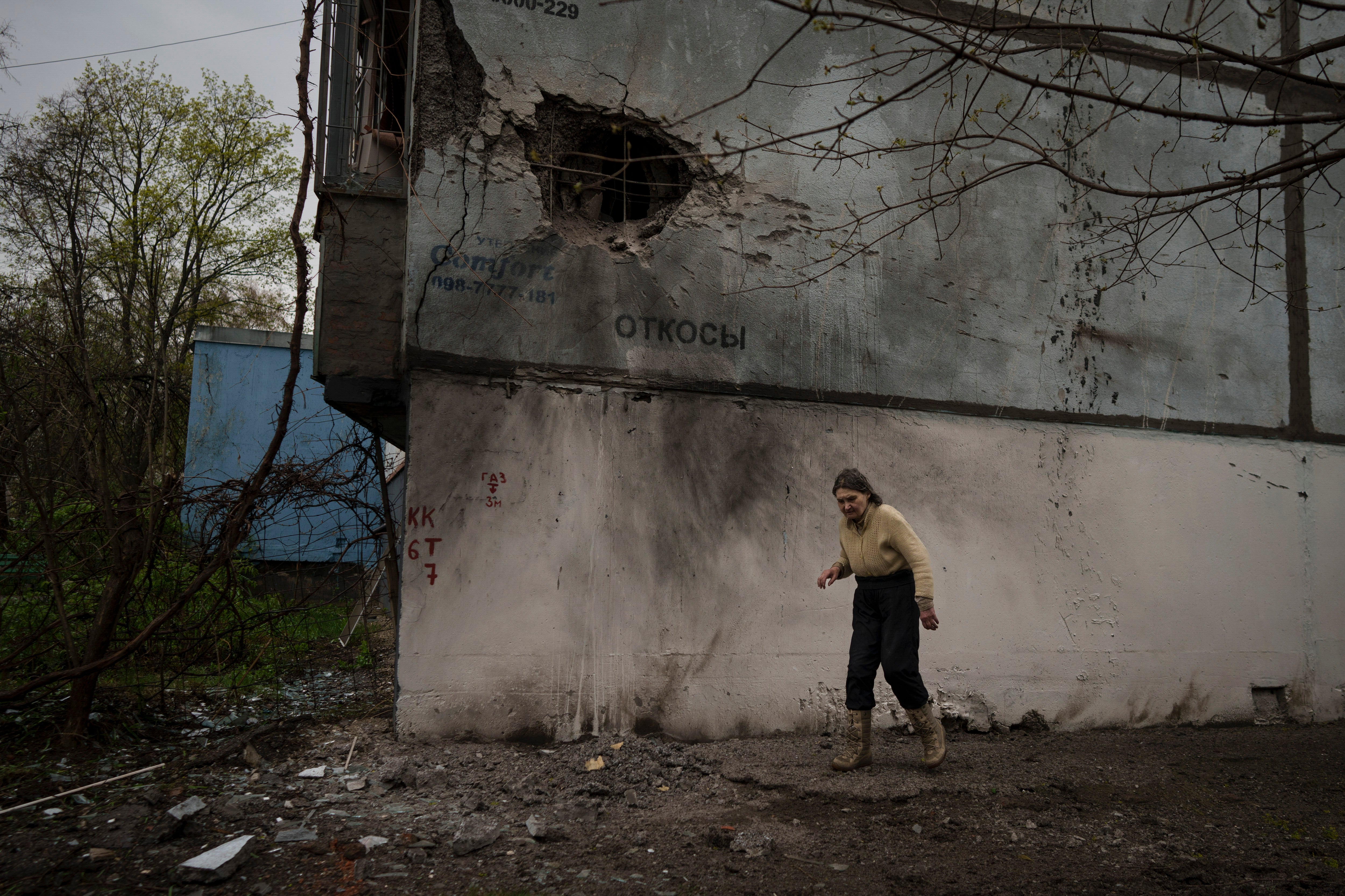 A woman walks next to a damaged building after a Russian bombardment in Kharkiv