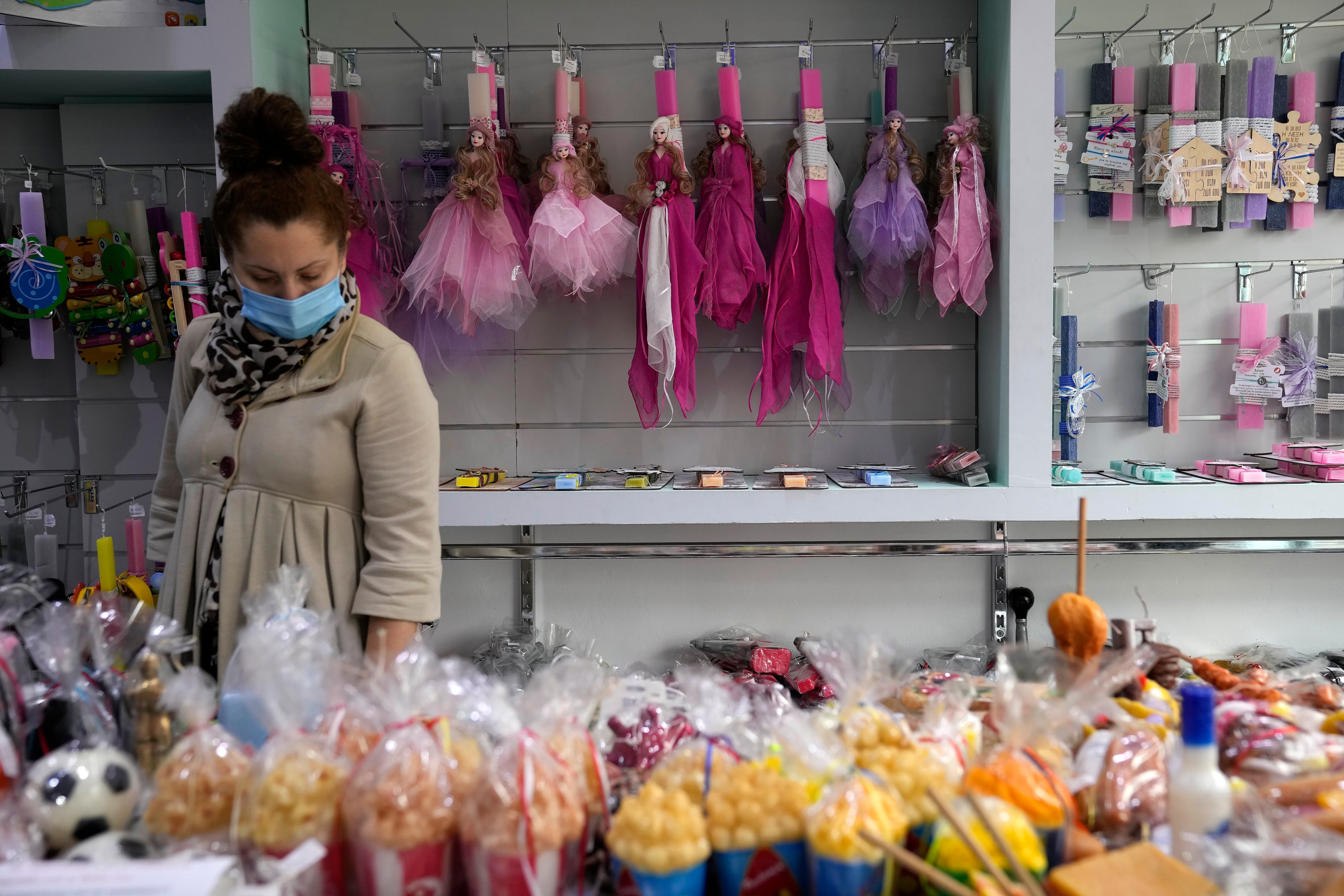 A woman checks for candles at a store in Athens, Greece