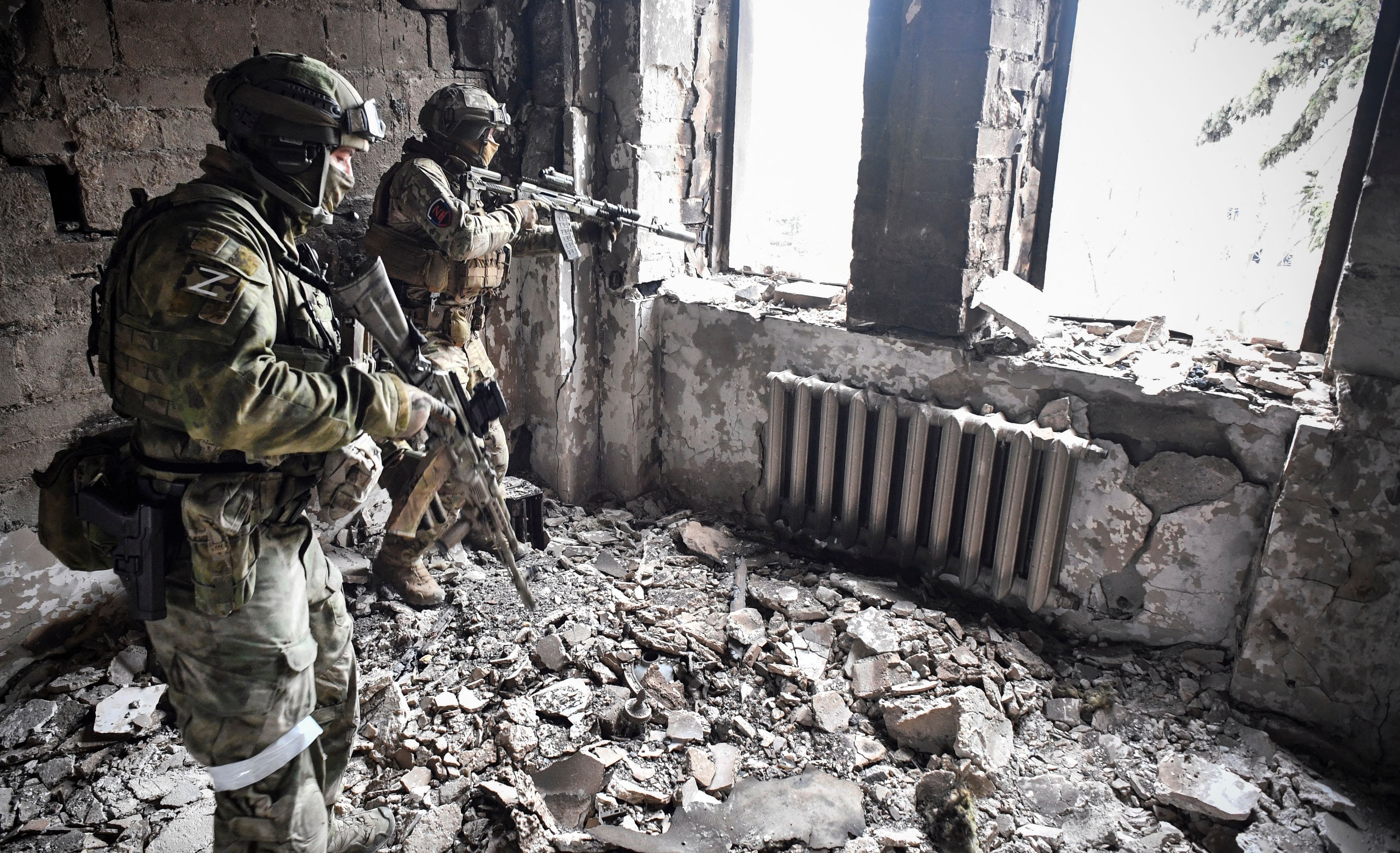 Two Russian soldiers patrol the remains of the Mariupol drama theatre