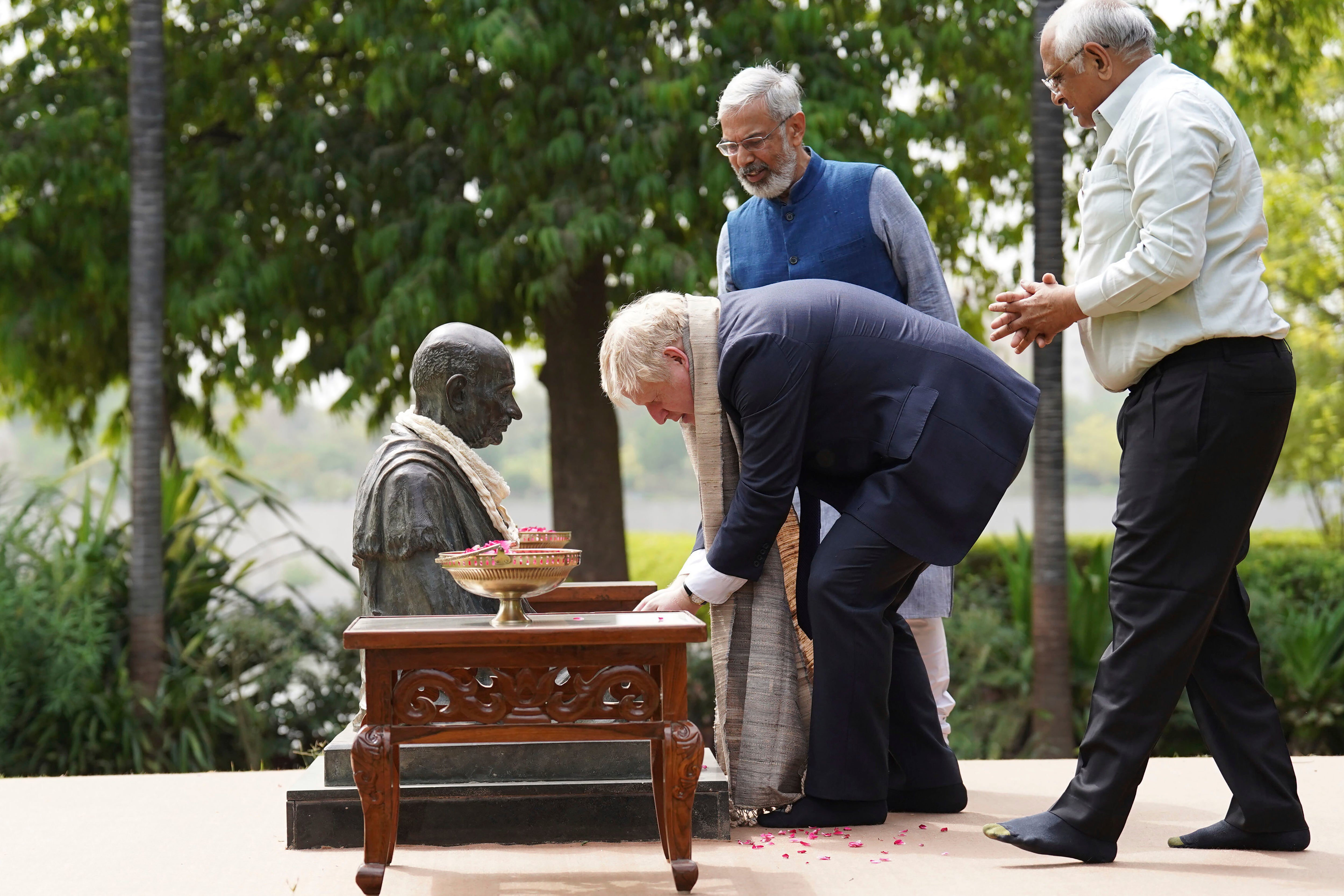 The prime minister places a garland around the neck of a statue of Mahatma Gandhi during a cultural tour in India