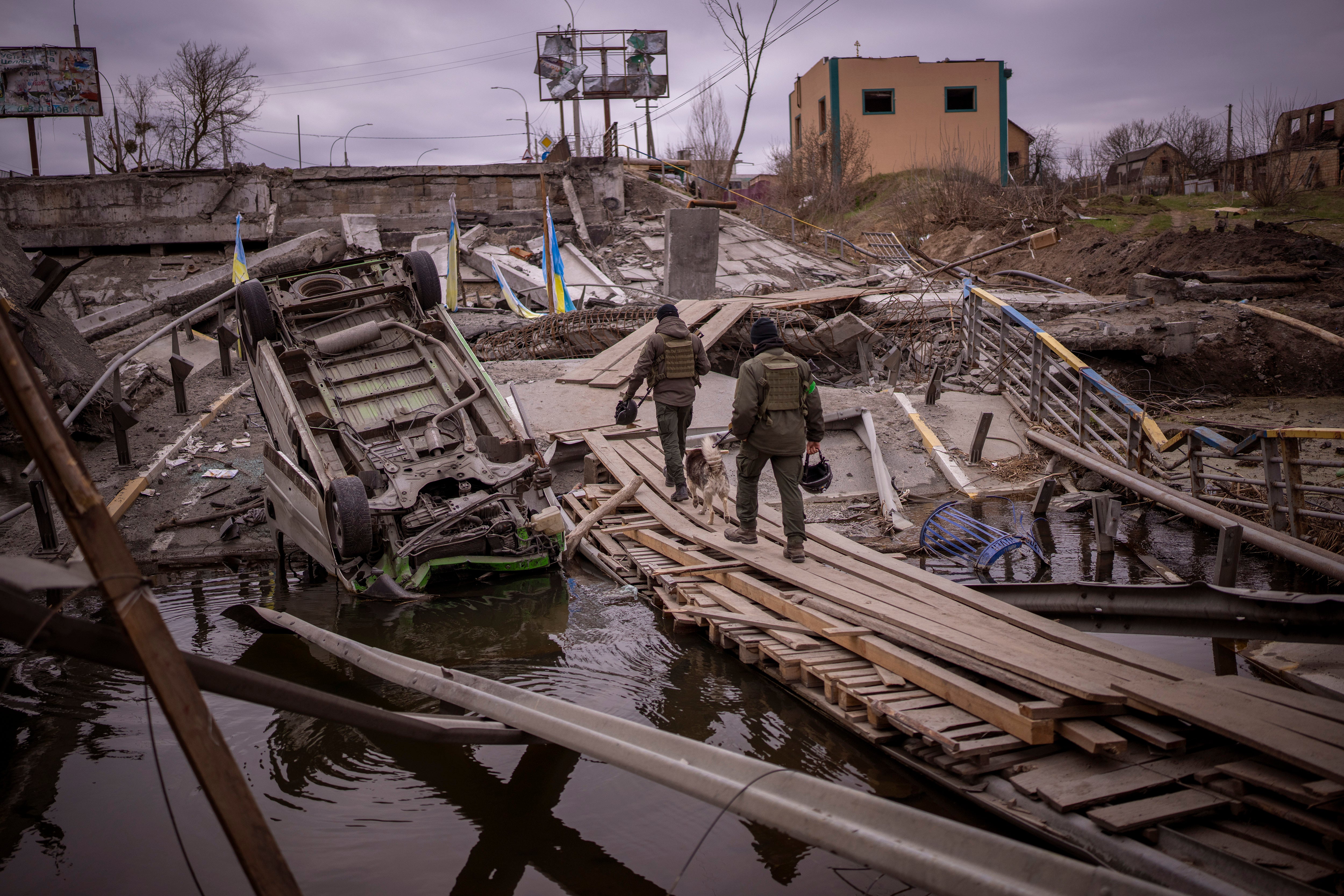 Ukrainian soldiers walk on a destroyed bridge in Irpin, on the outskirts of Kyiv (Emilio Morenatti/AP)