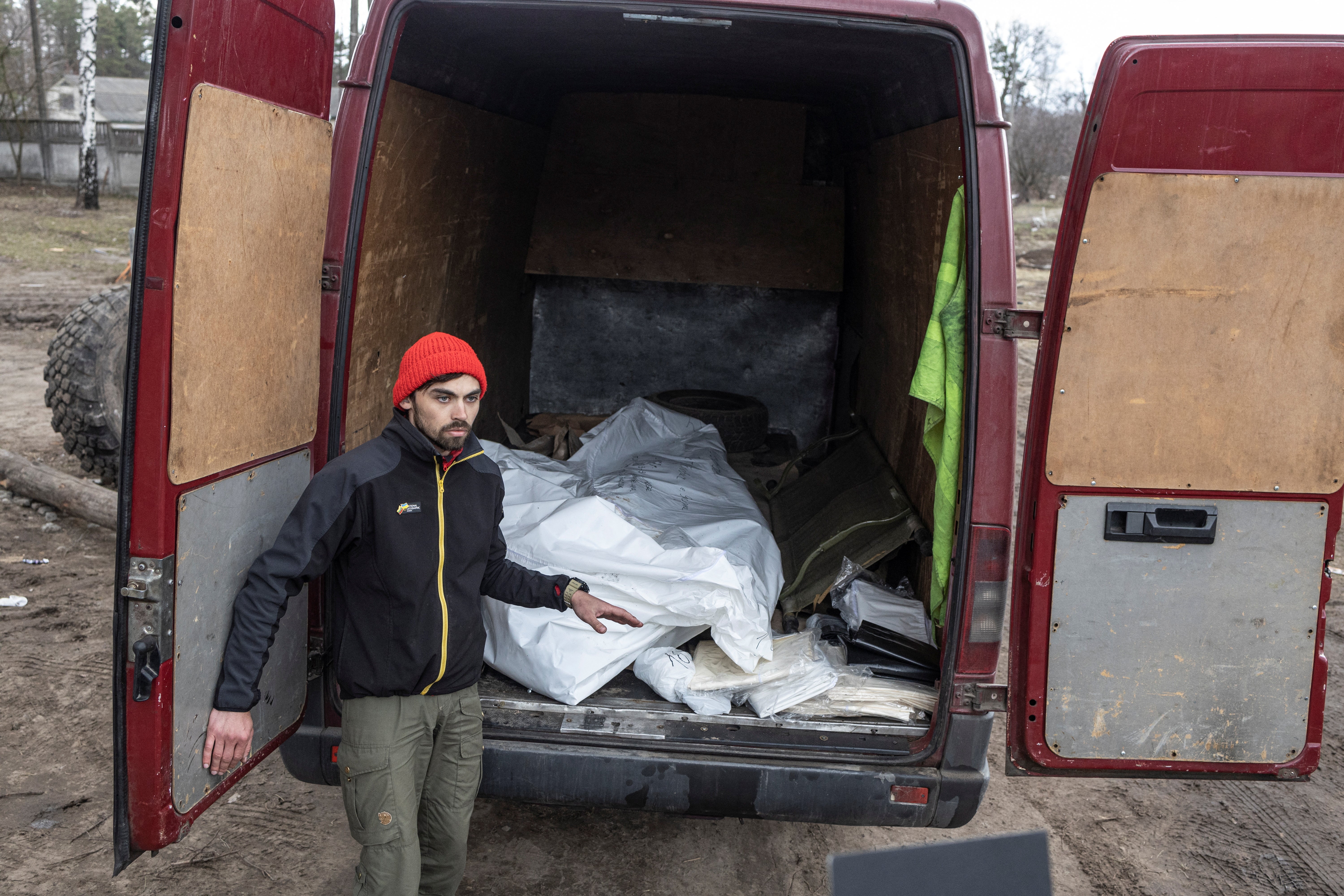 Vitalii Udod, a volunteer from Kyiv, stands next to a van loaded with two dead bodies