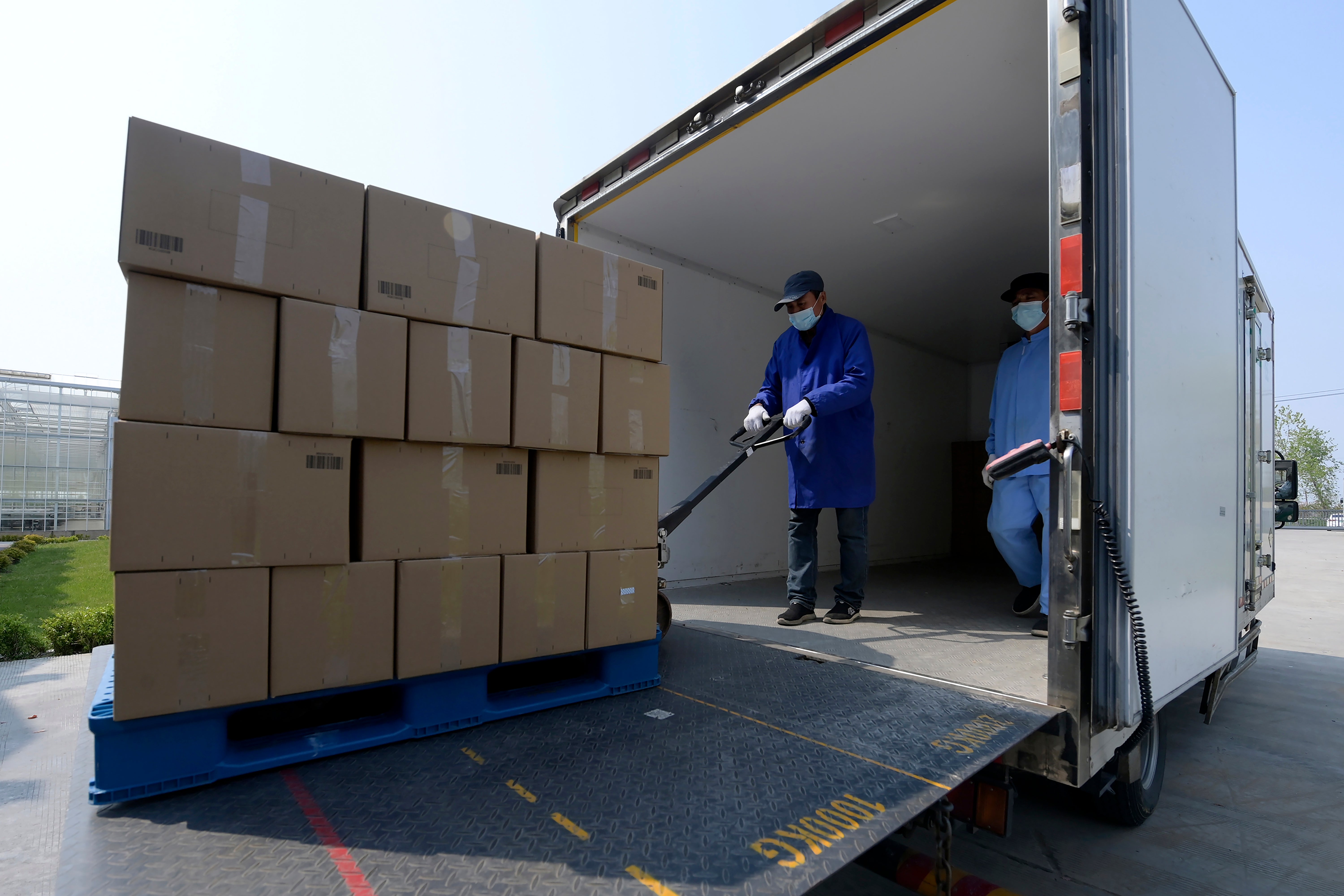 In this photo released by China’s Xinhua News Agency, workers load boxes of vegetables to be sent to urban neighborhoods at an agricultural facility in Shanghai, 19 April