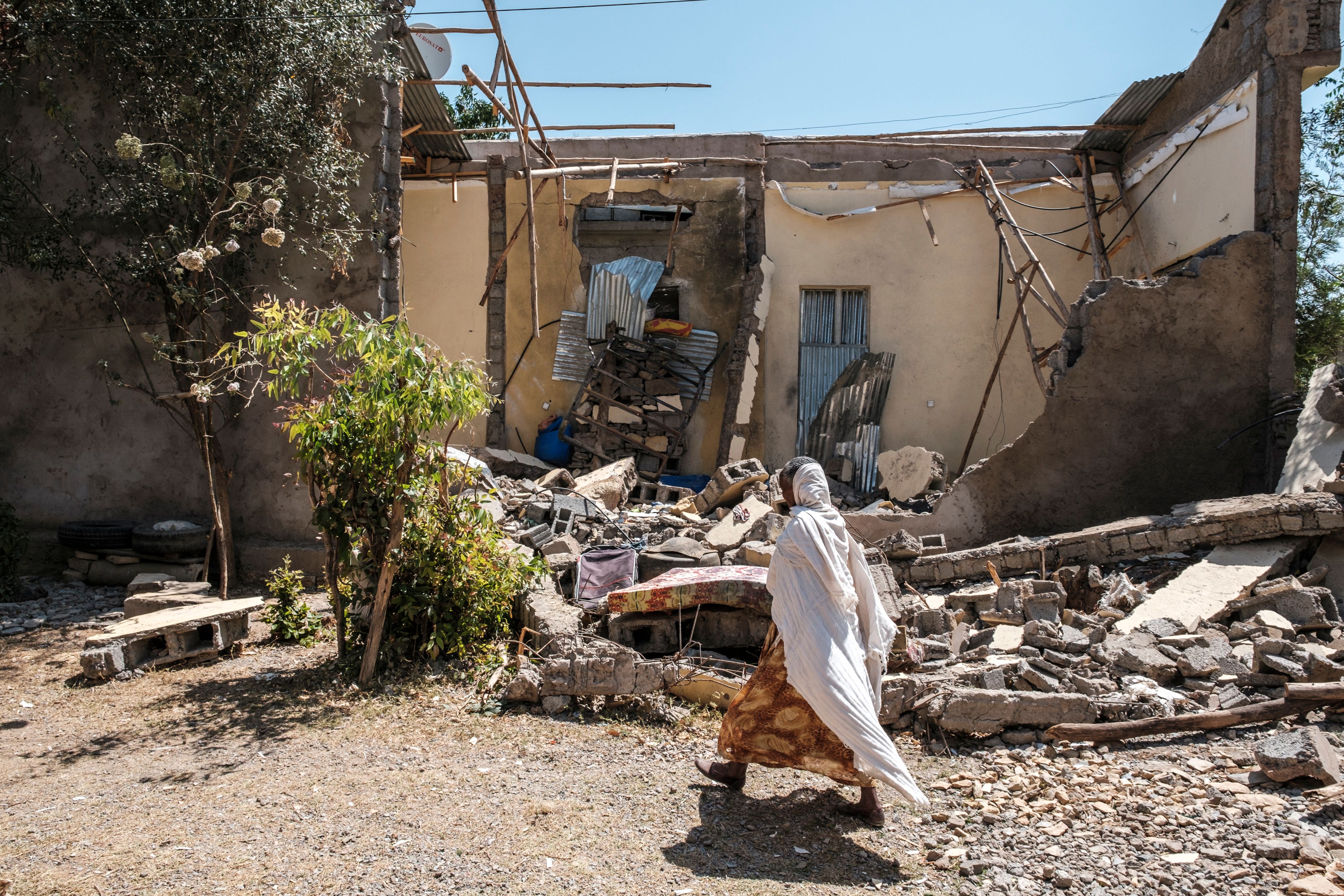 File photo: A woman walks in front of a damaged house shelled as federal-aligned forces entered the city, in Wukro, north of Mekele, in March 2021