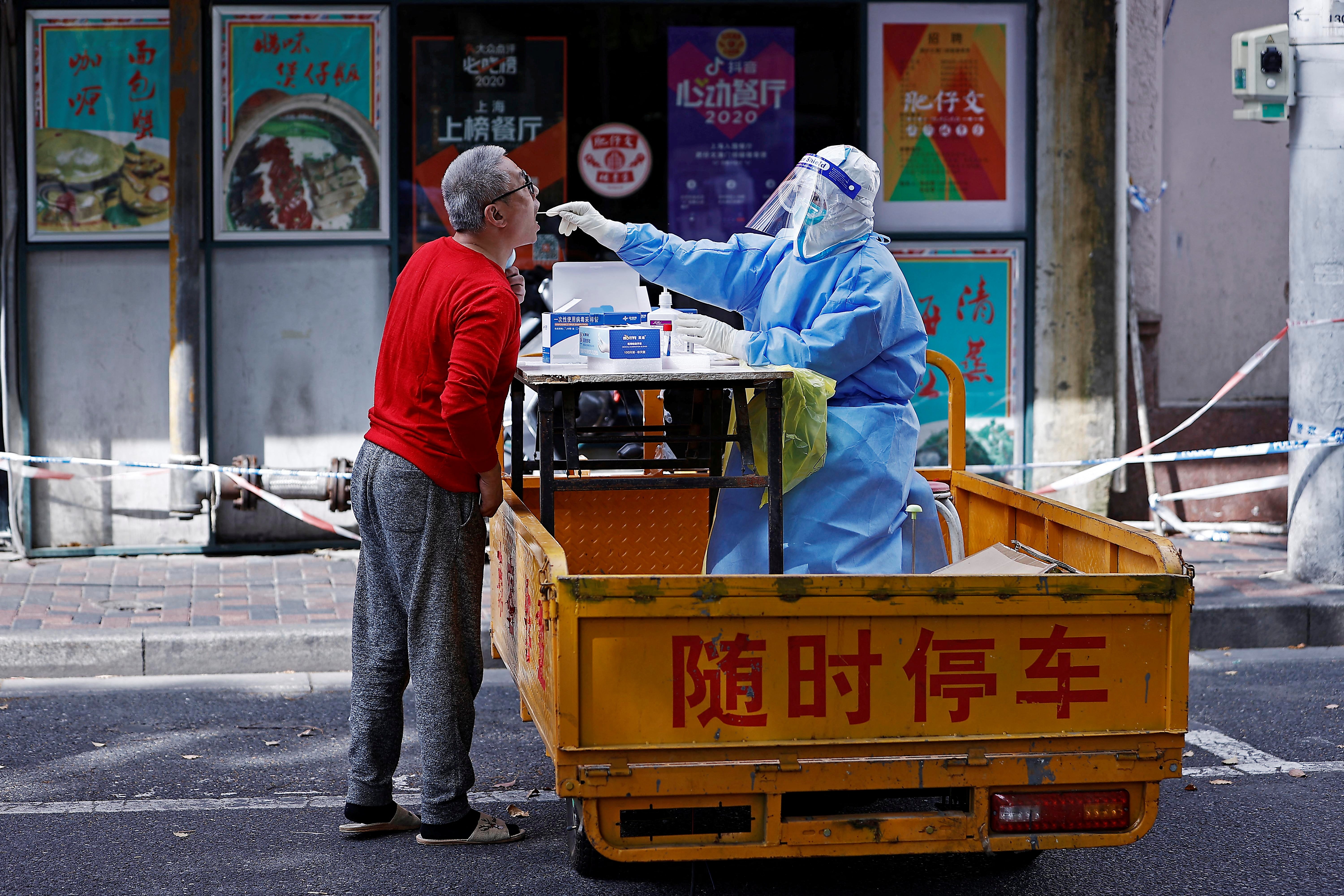 A medical worker in a protective suit collects a swab from a resident