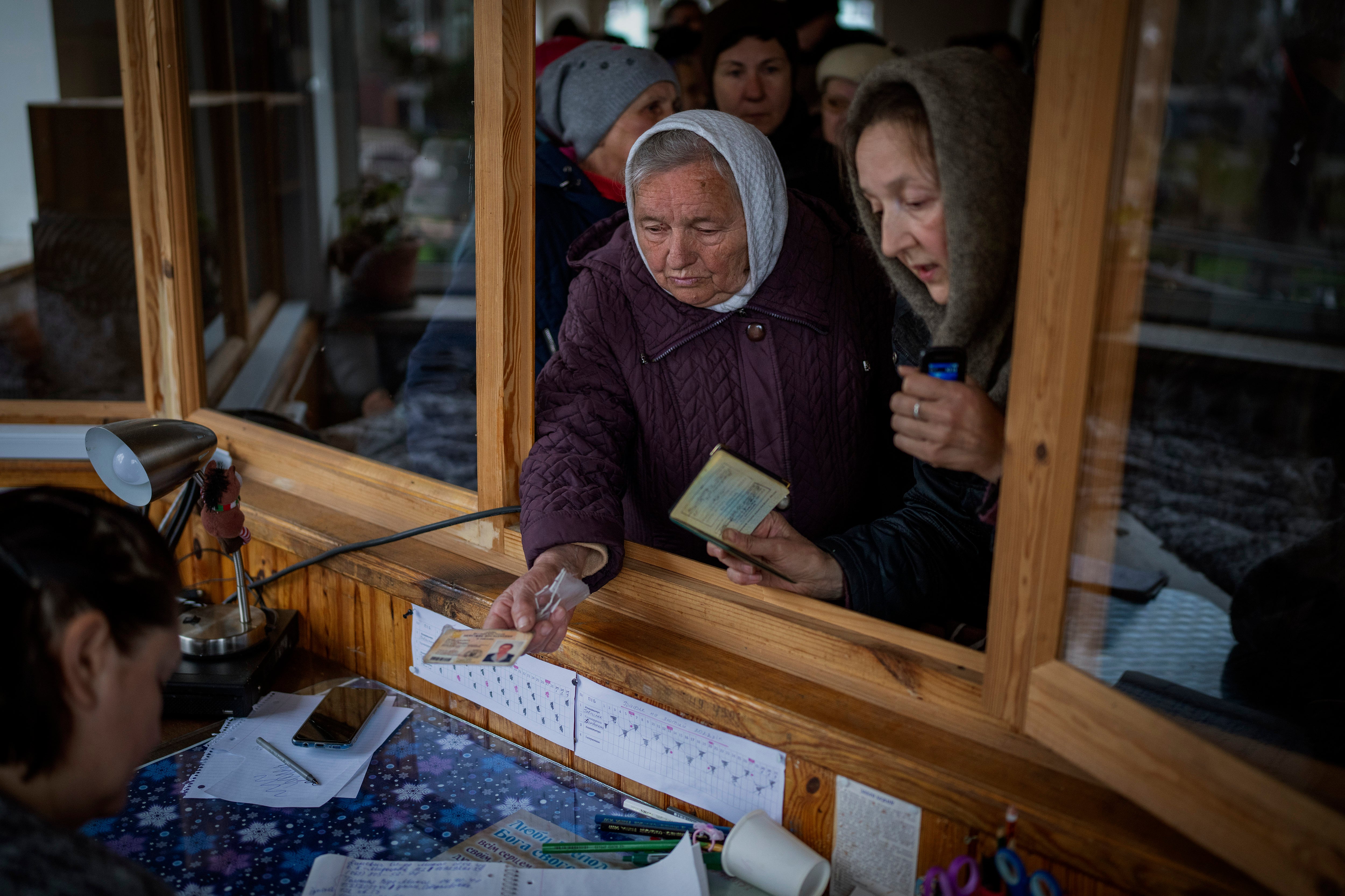 Ukrainian women show their ID inside a church to receive humanitarian aid donated by the European Union in Bucha