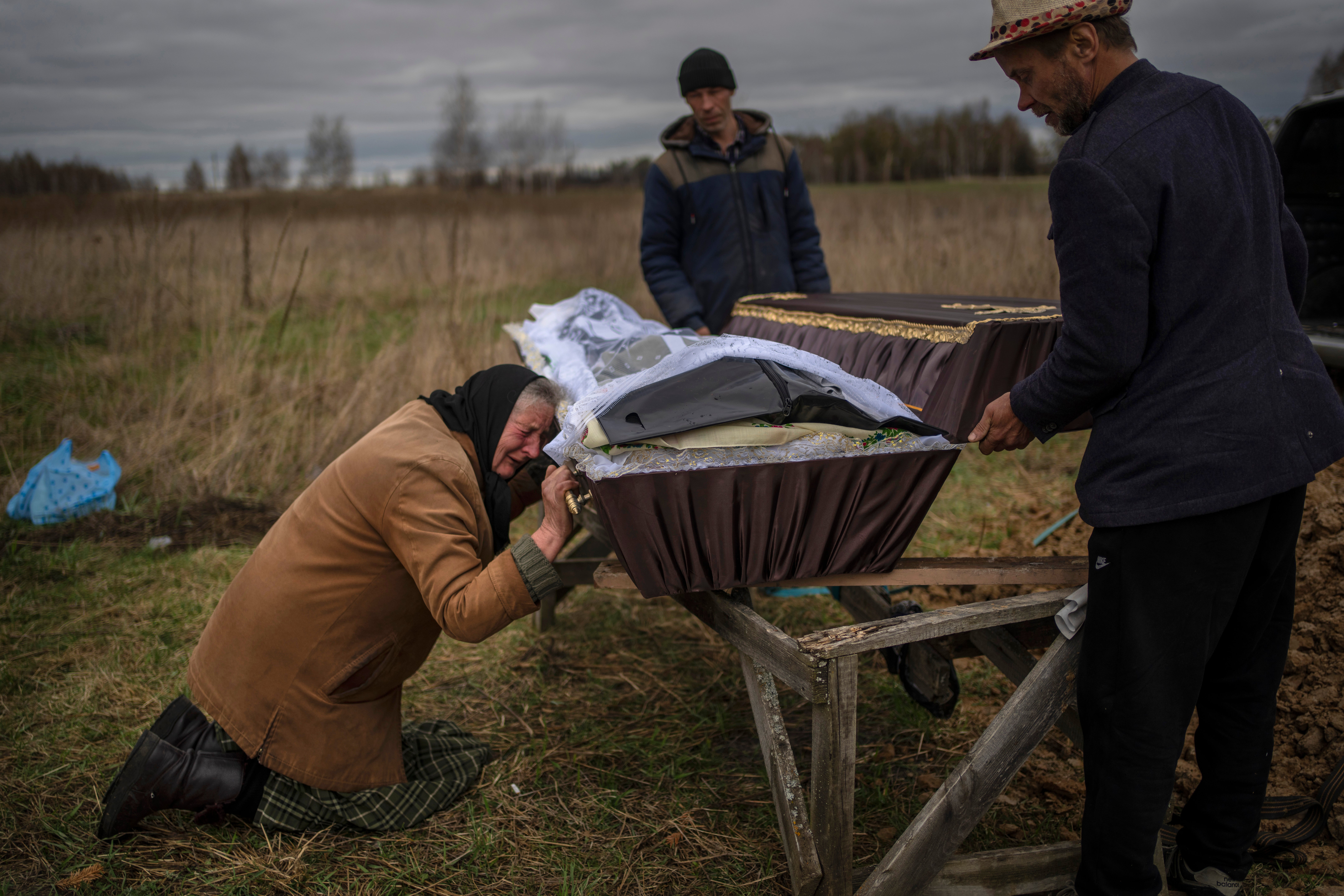 A woman cries while holding the coffin of her son Vadym, 48, who was killed by Russian soldiers in Bucha