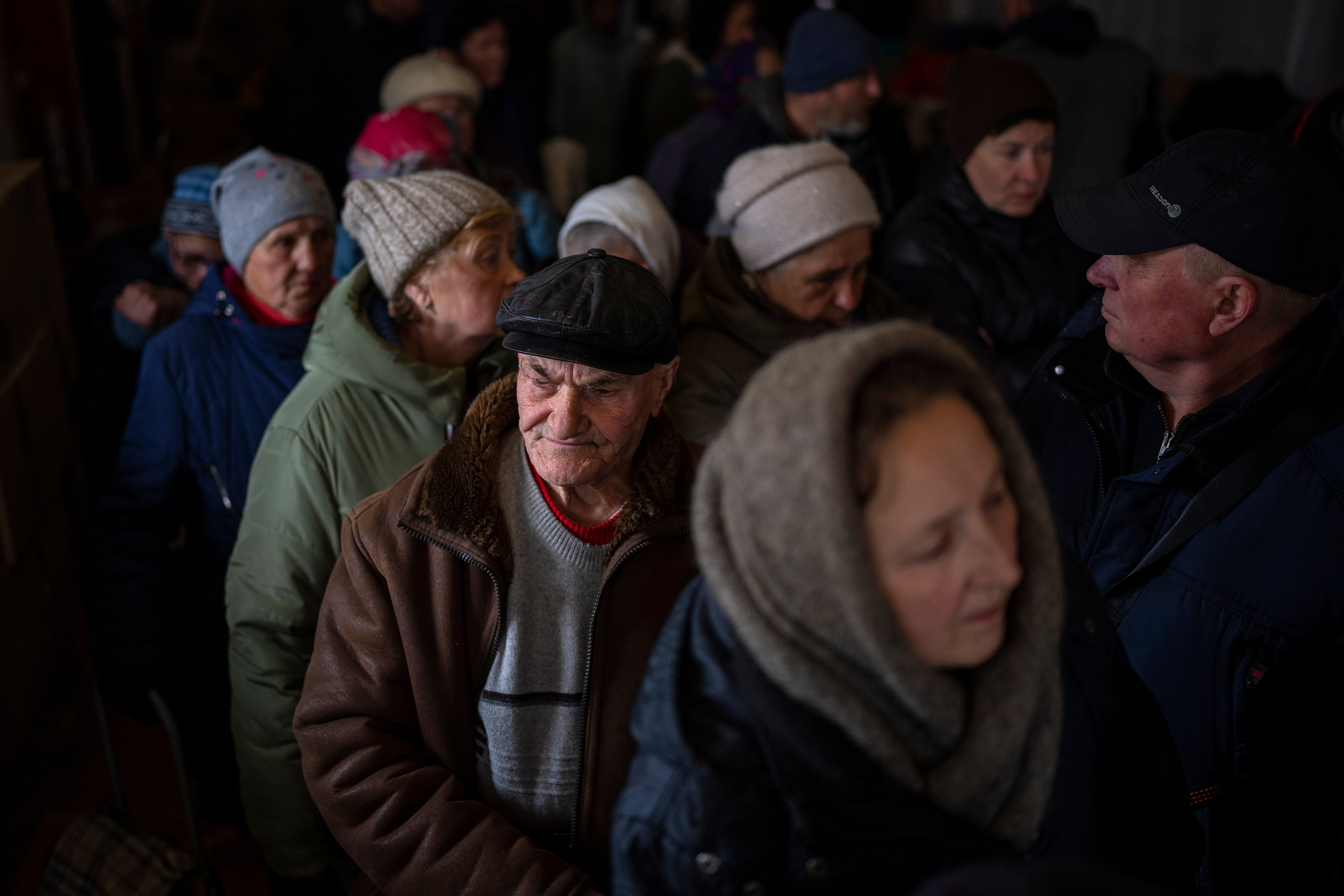 Ukrainian men queue inside a church in Bucha to receive humanitarian aid donated from the European Union