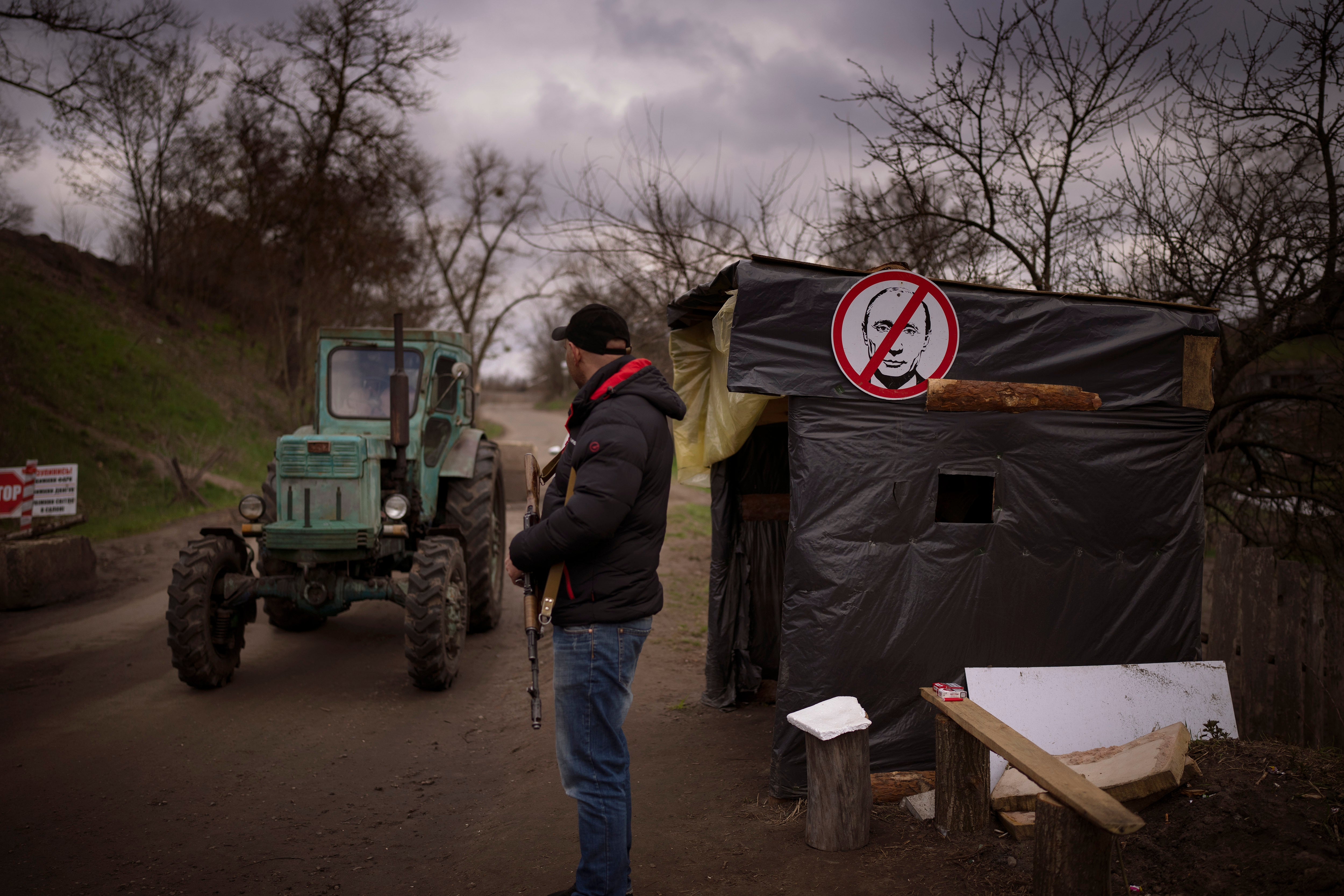 A civil defence volunteer stands guard at a checkpoint controlling the traffic near Kyiv