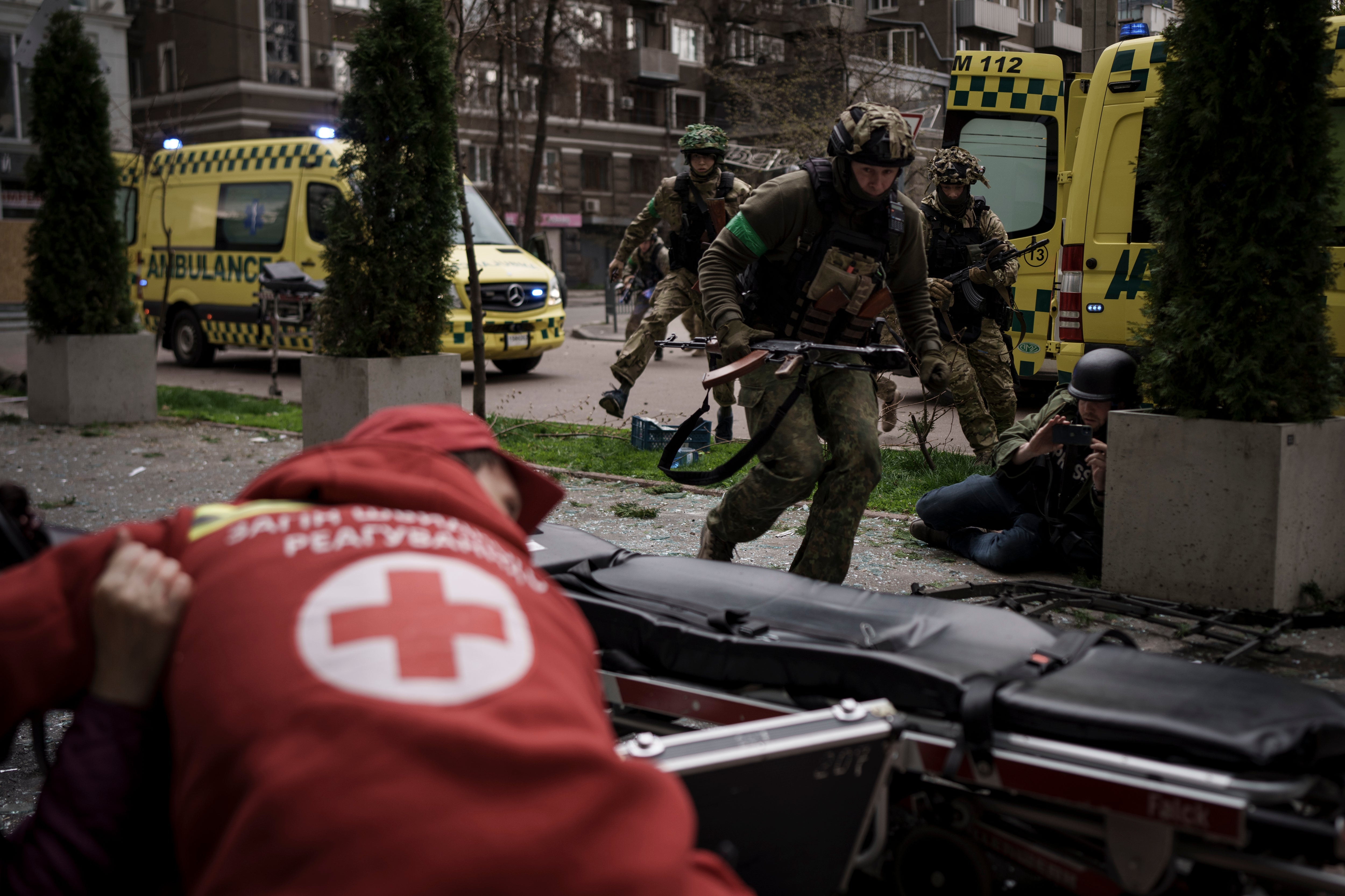 Ukrainian servicemen run for cover as explosions are heard during a Russian attack in downtown Kharkiv