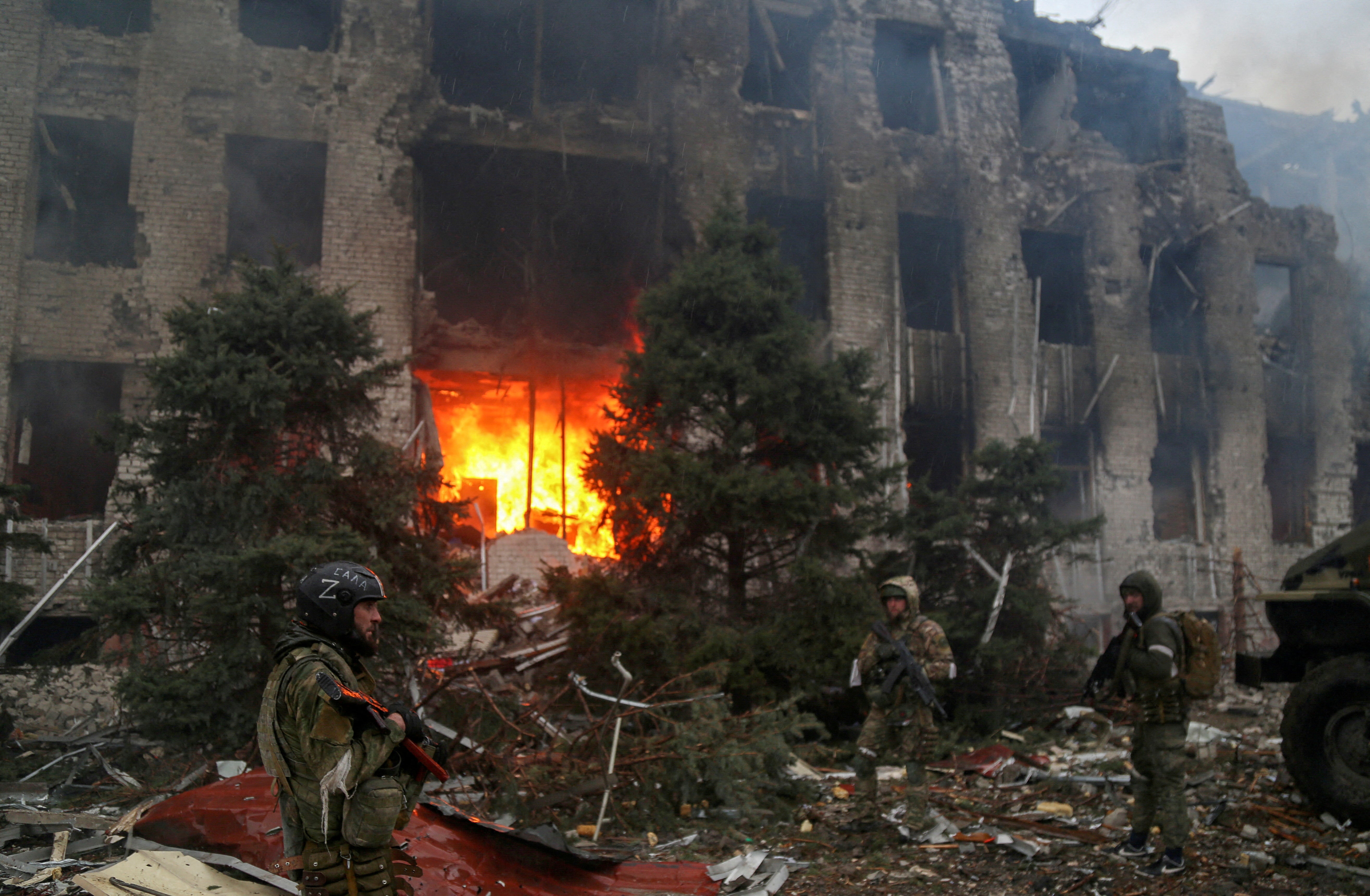 Service members of pro-Russian troops, including fighters of the Chechen special forces unit, stand in front of the destroyed administration building of Azovstal Iron and Steel Works