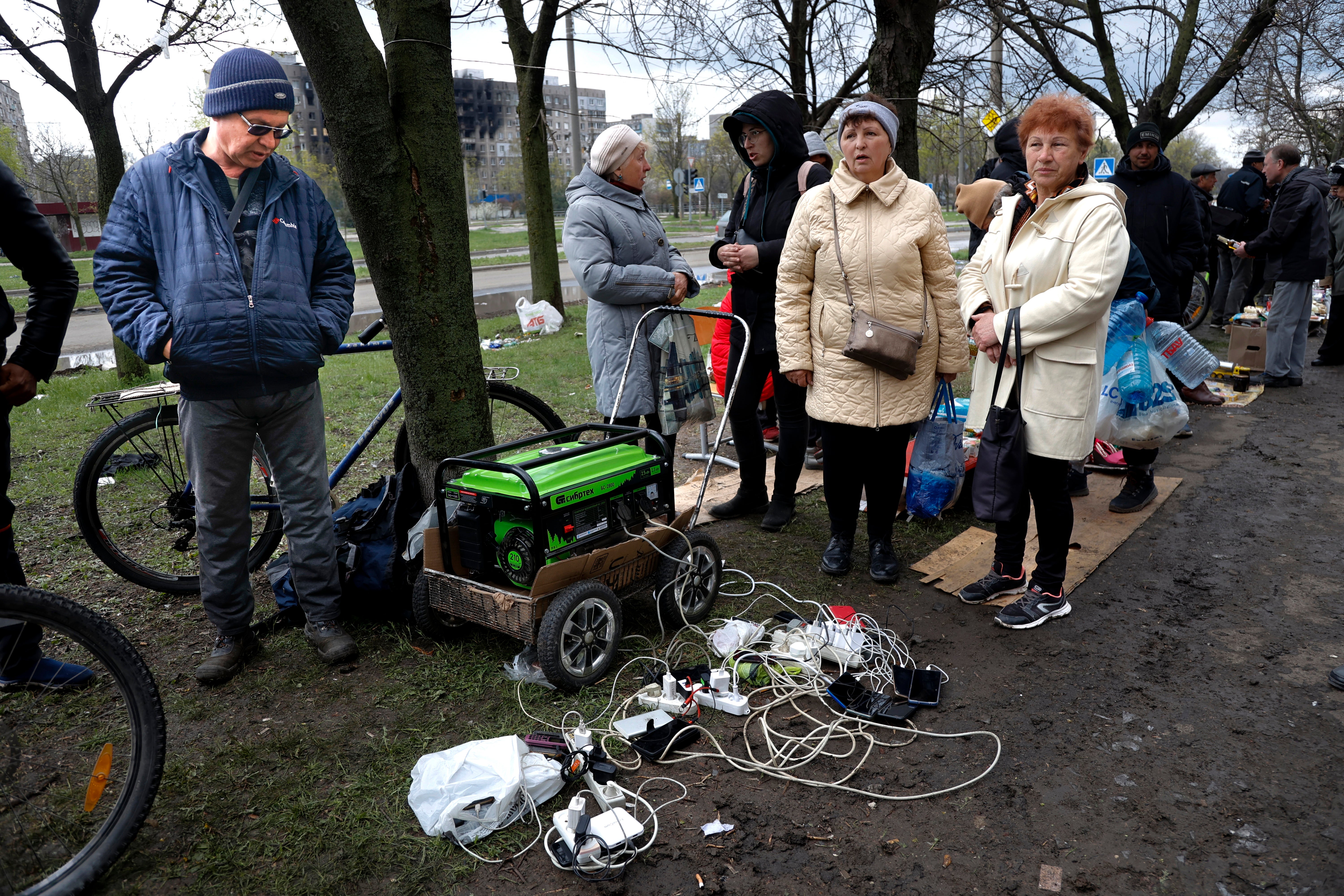 Local residents gather near a generator to charge their mobile devices in an area controlled by Russian-backed separatist forces in Mariupol