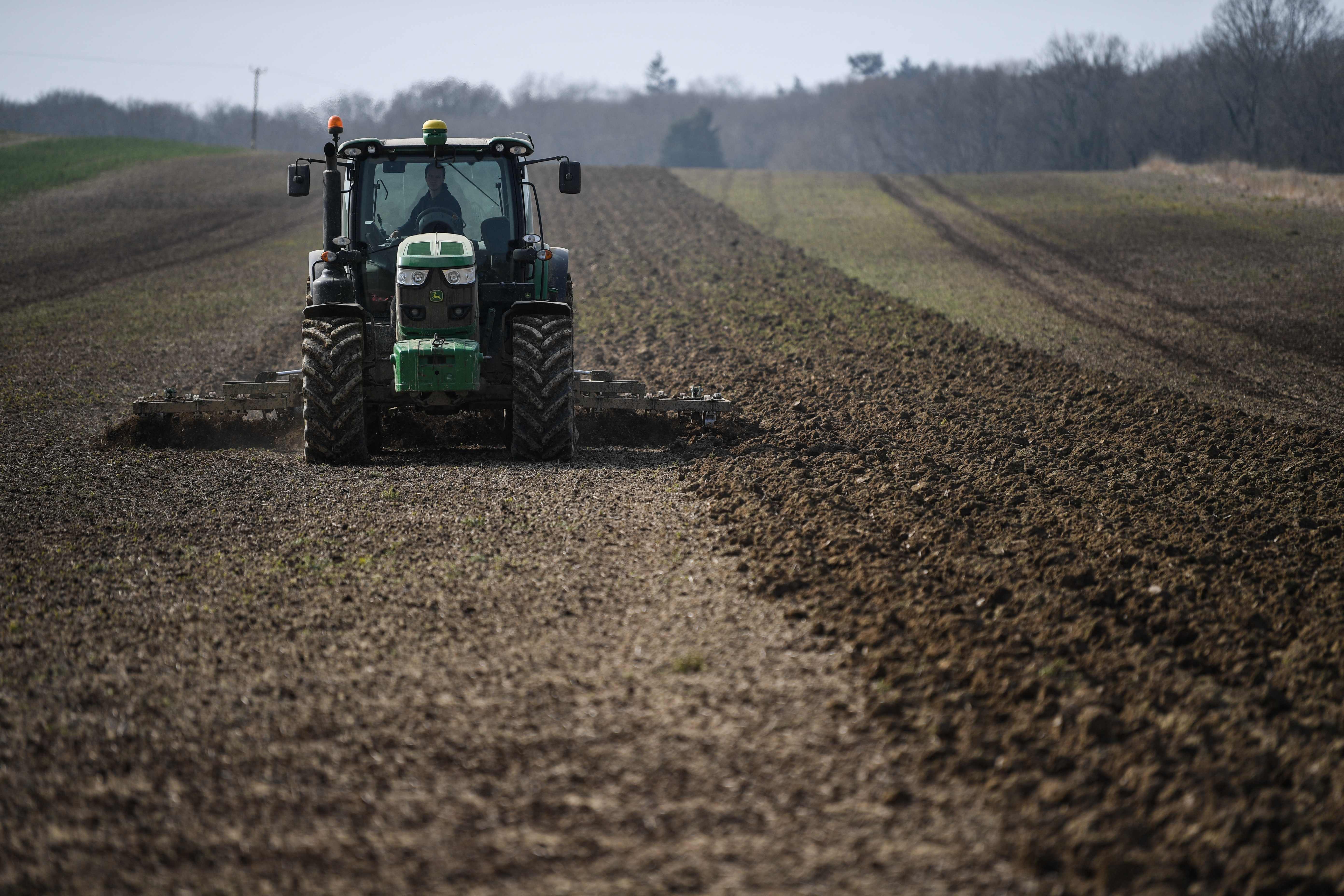 A tractor cultivates the ground for rapeseed oil crops at the Westons Farm, in Itchingfield