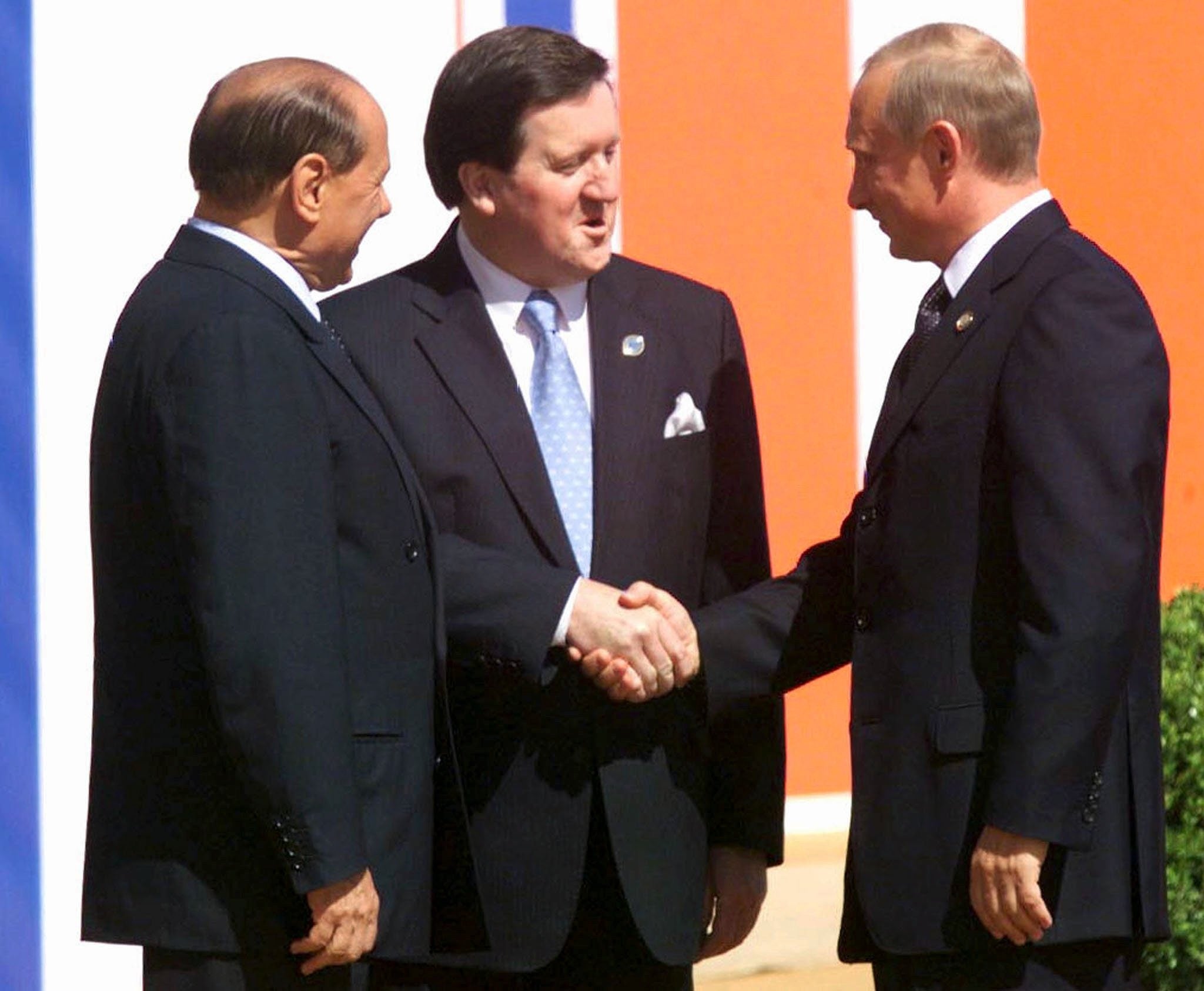 Putin shakes hands with the Nato secretary general George Robertson, as Italian prime minister Silvio Berlusconi watches on in 2002