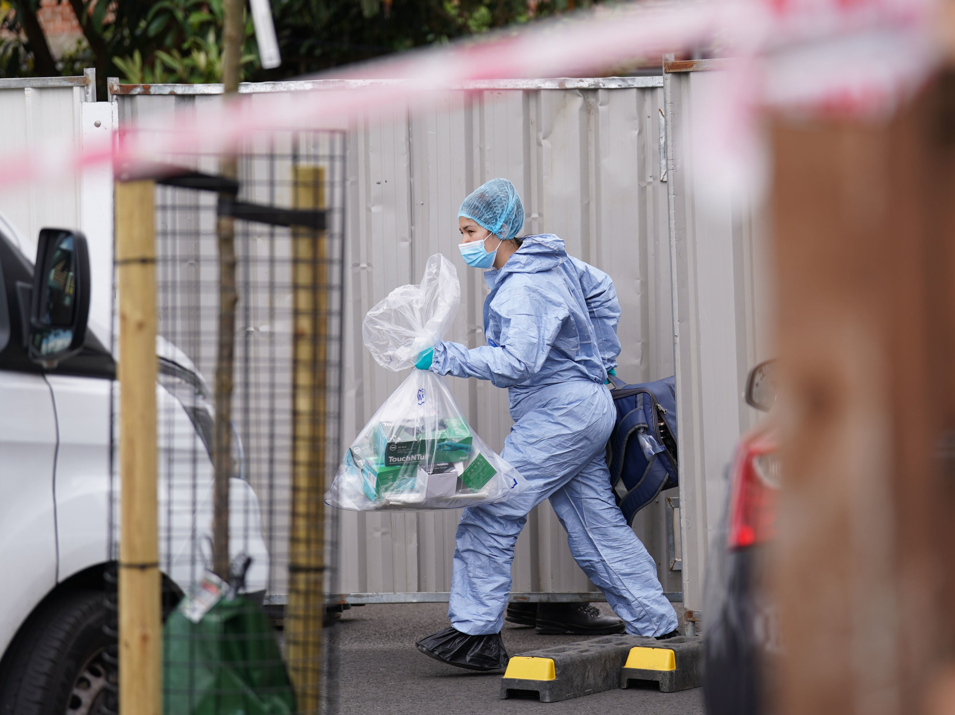 A police officer in a forensic suit is seen removing items from the house in Bermondsey