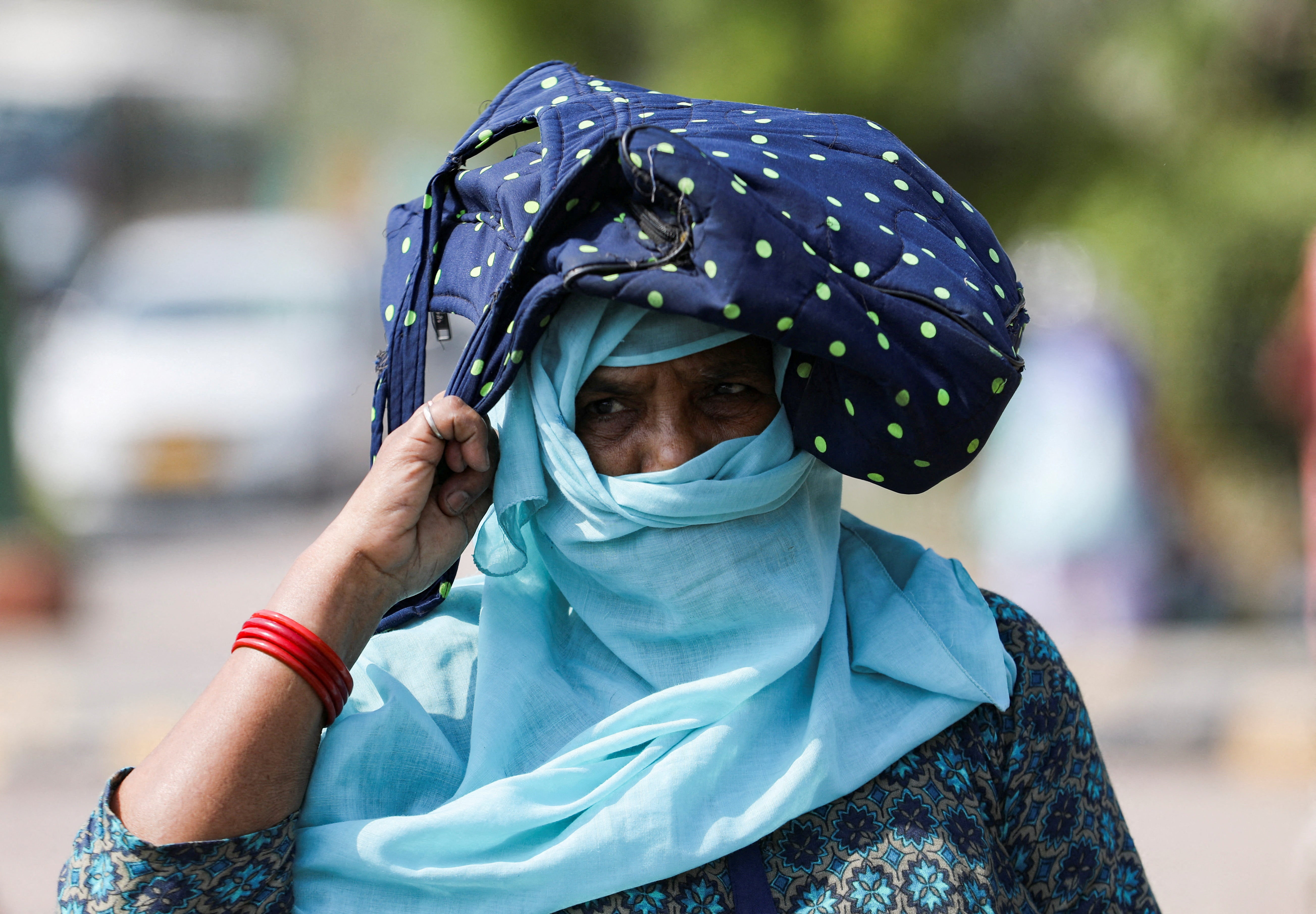 A woman uses her bag to protect herself from the sun in Delhi