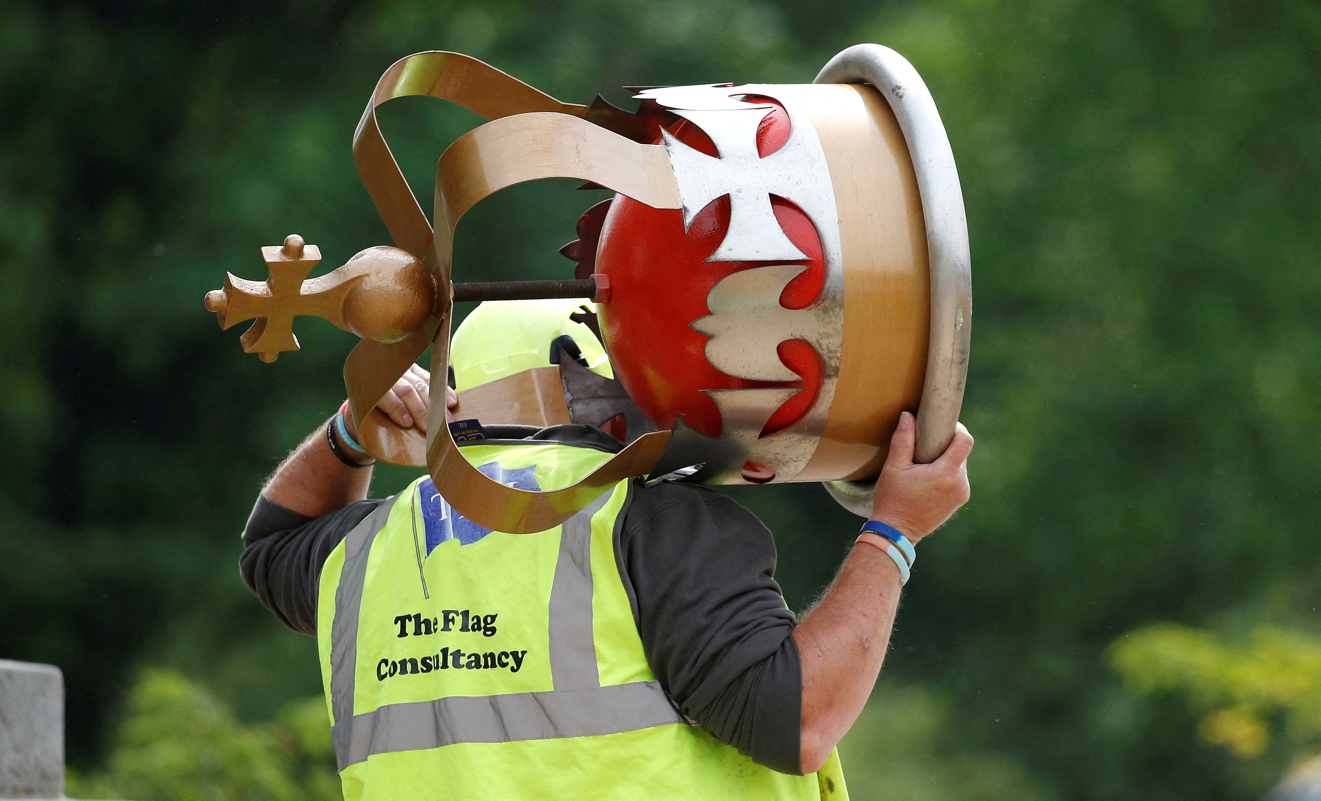 A worker carries a decorative crown prior to placing it atop a flag pole ahead of planned celebrations for Queen Elizabeth's Platinum Jubilee, facing Buckingham Palace, in London on 28 April 2022