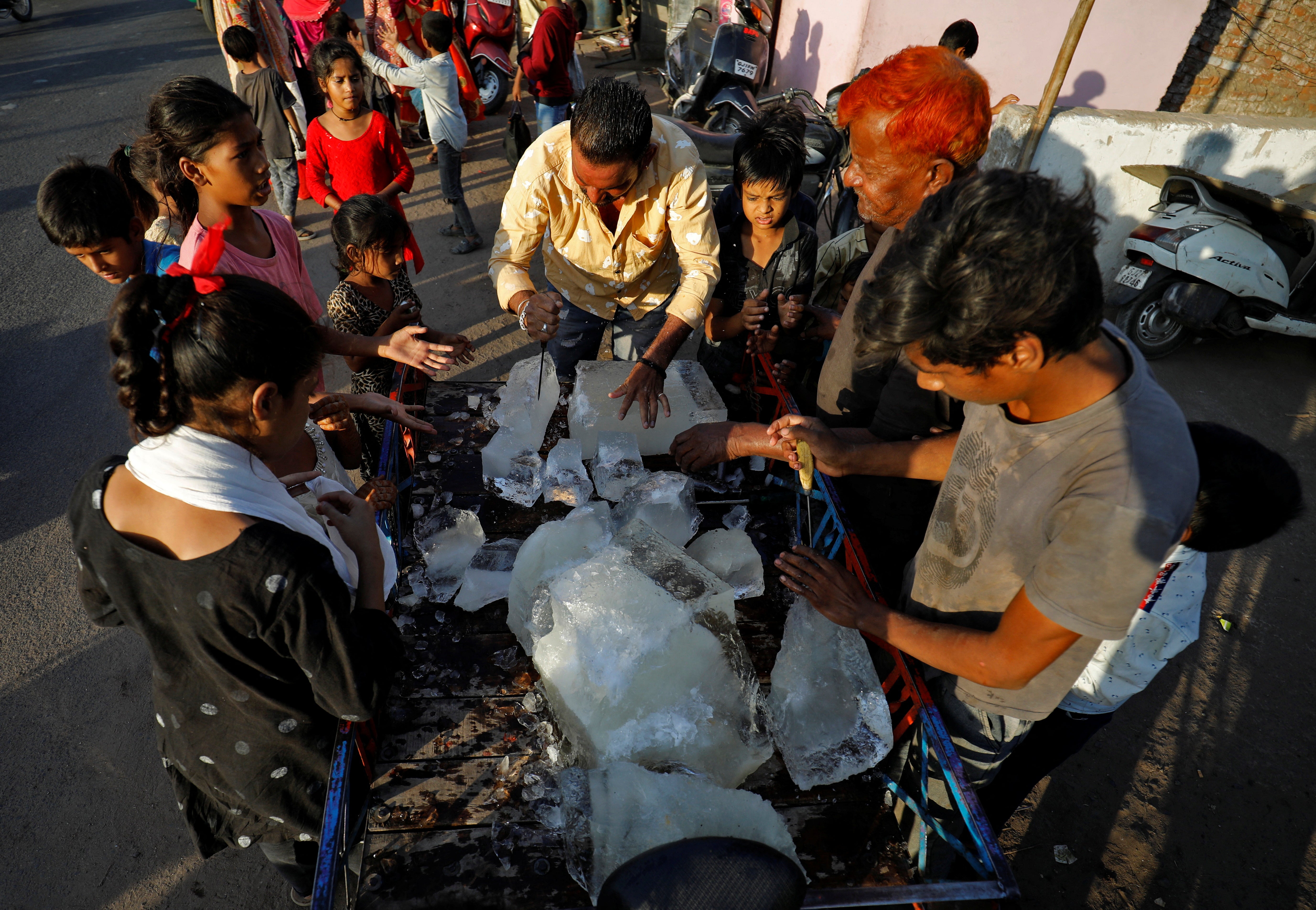 A man breaks a block of ice to distribute it among the residents of a slum during hot weather in Ahmedabad, India, on Thursday.