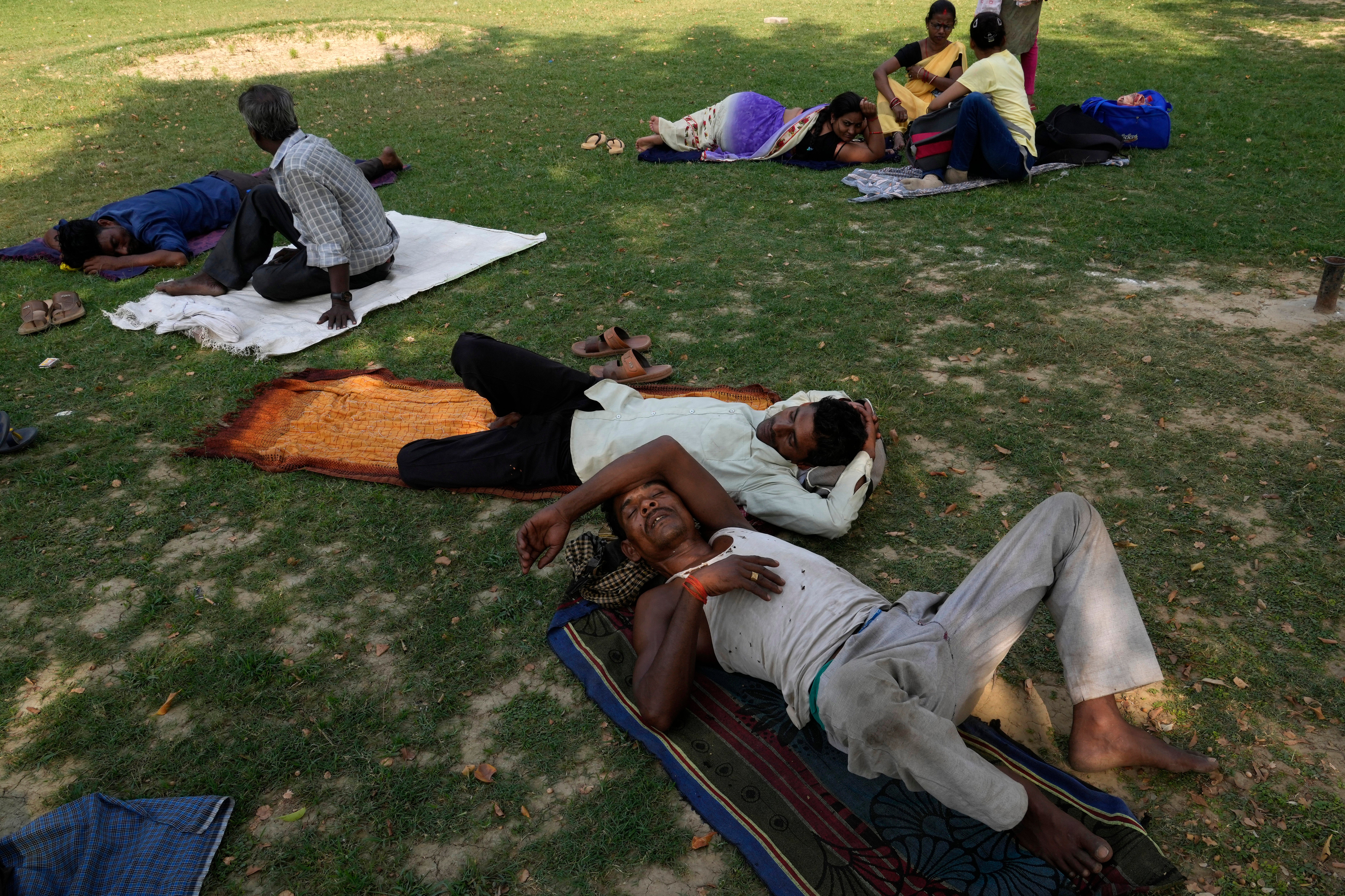 People rest in the shade of a tree on a hot summer afternoon in Lucknow in the central Indian state of Uttar Pradesh, Thursday, 28 April 2022