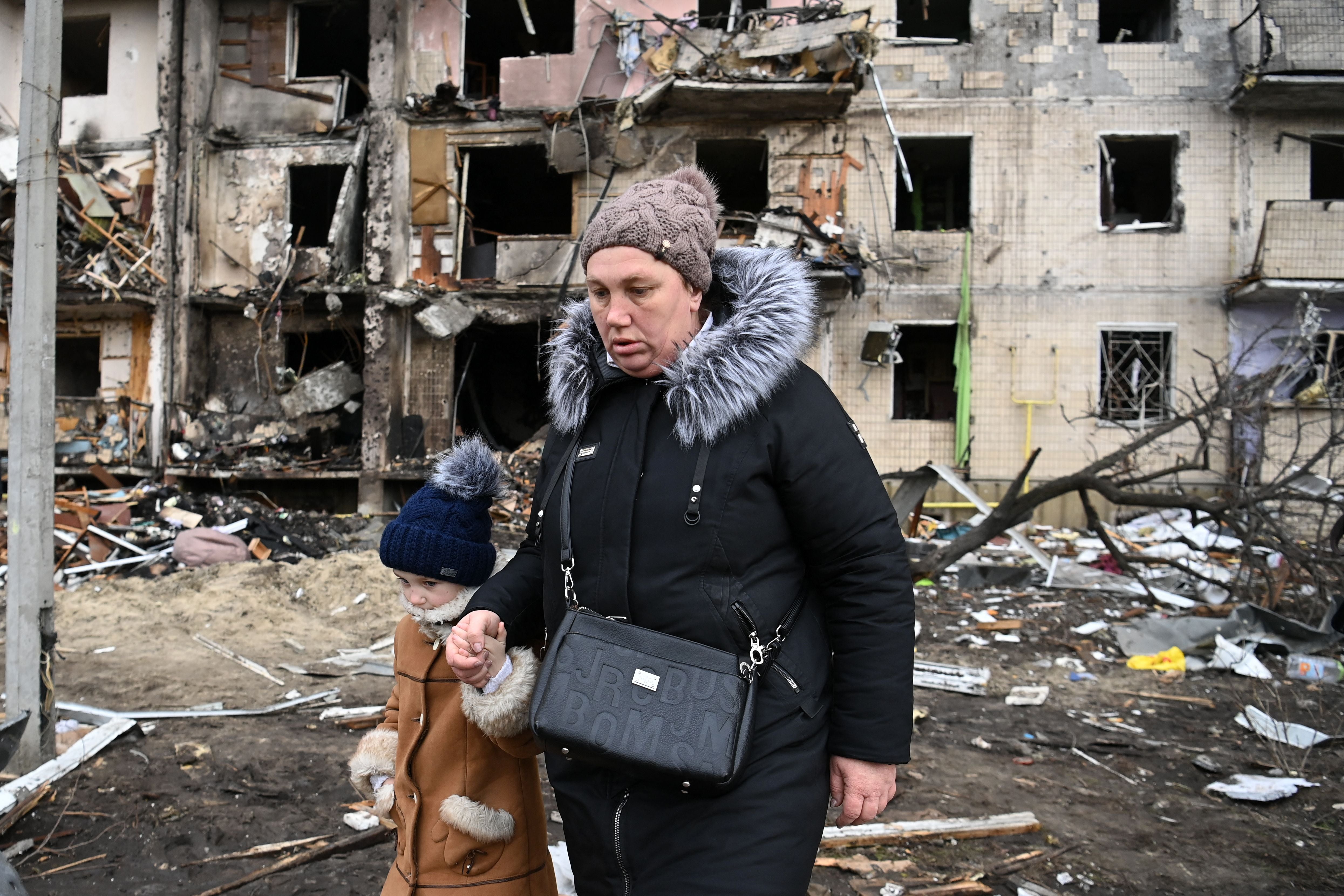 A woman and child walk through a residential area of Kyiv in the second day of the invasion