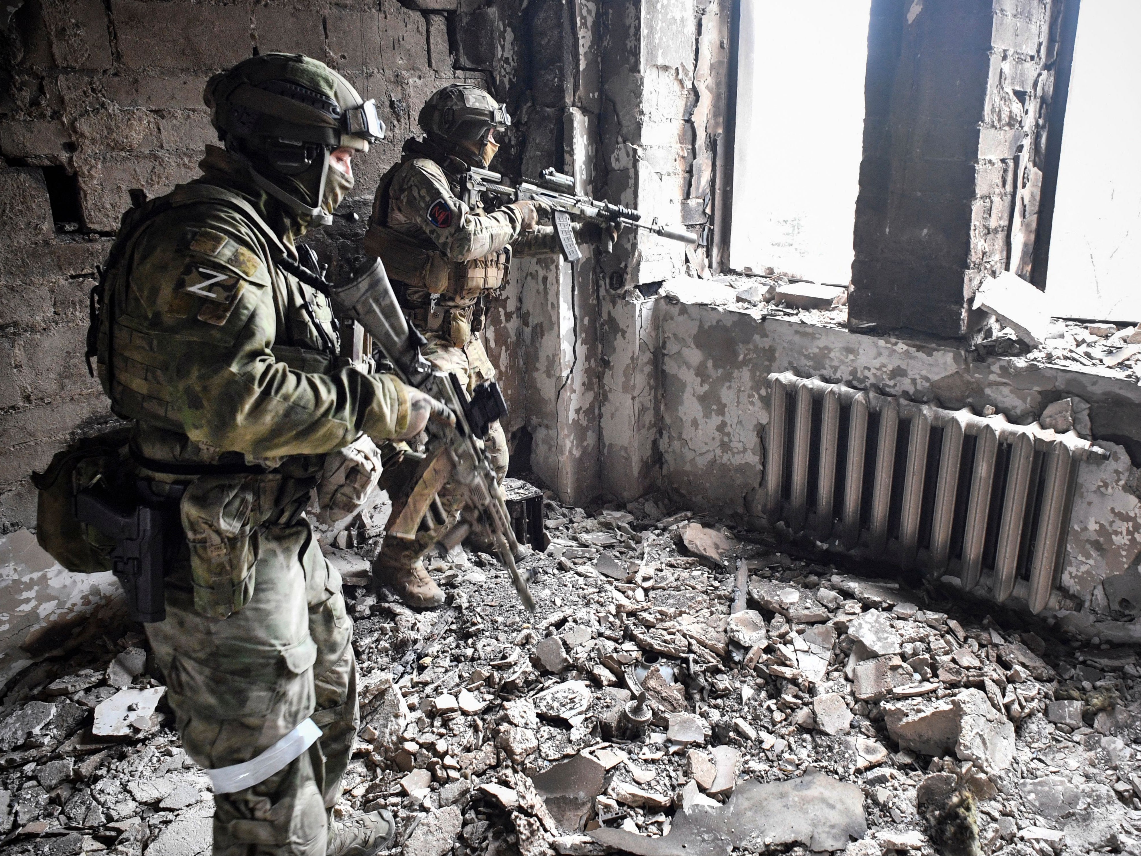 Two Russian soldiers patrol in the Mariupol drama theatre a month after it was bombed