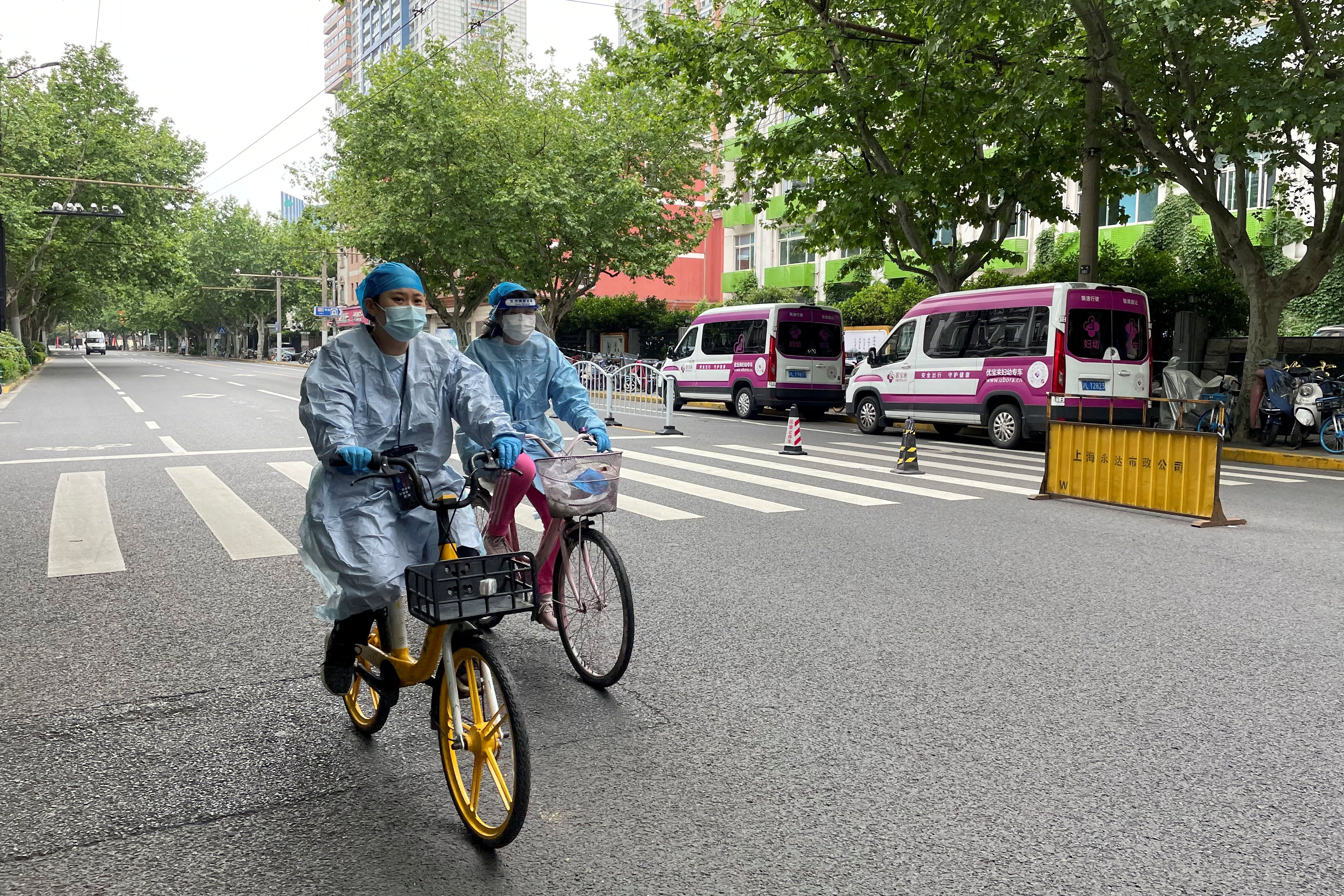 Workers in protective suits ride bicycles during the outbreak