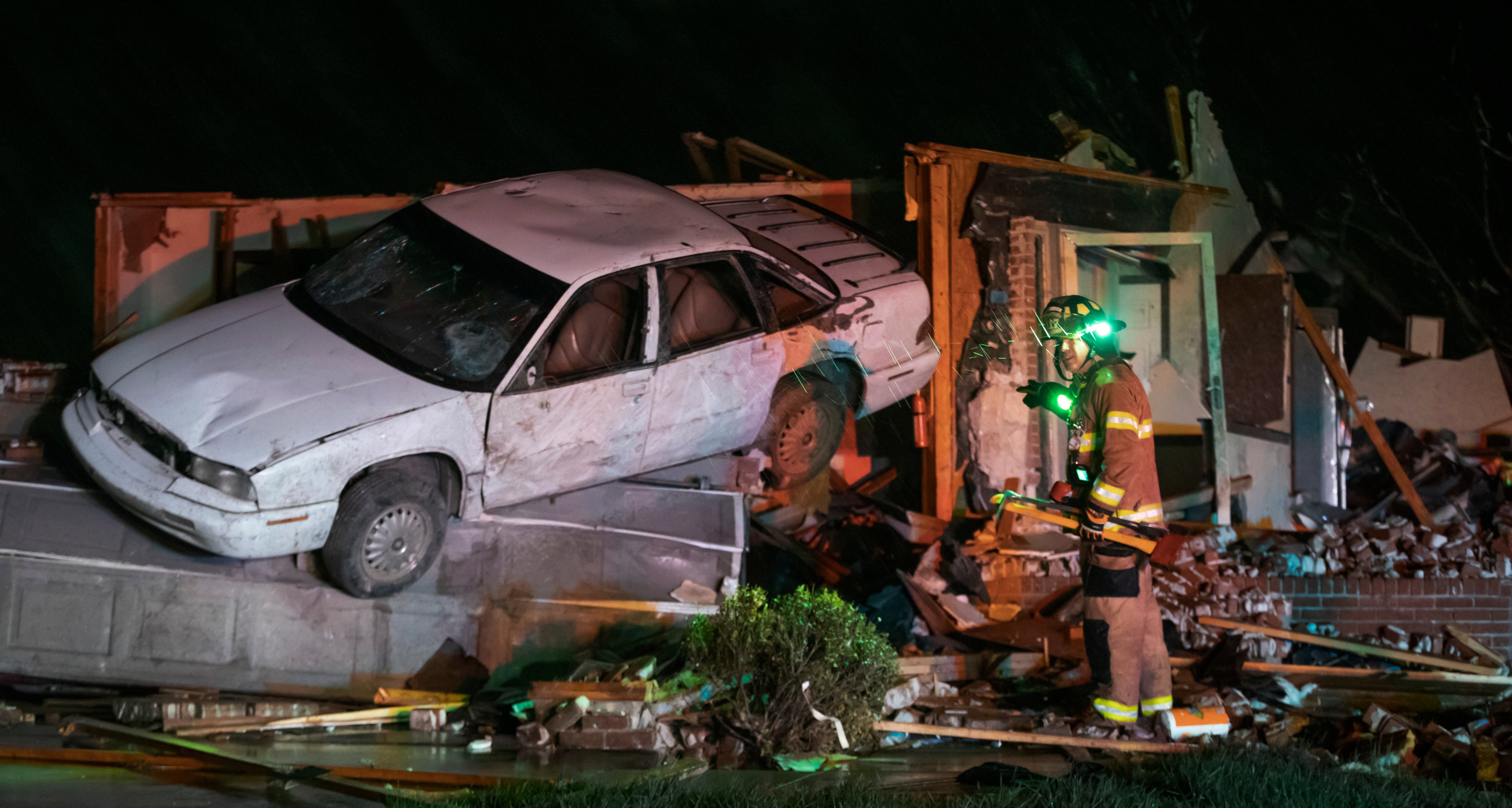 A firefighter searches a home in Andover on Friday night after a tornado ripped through the area