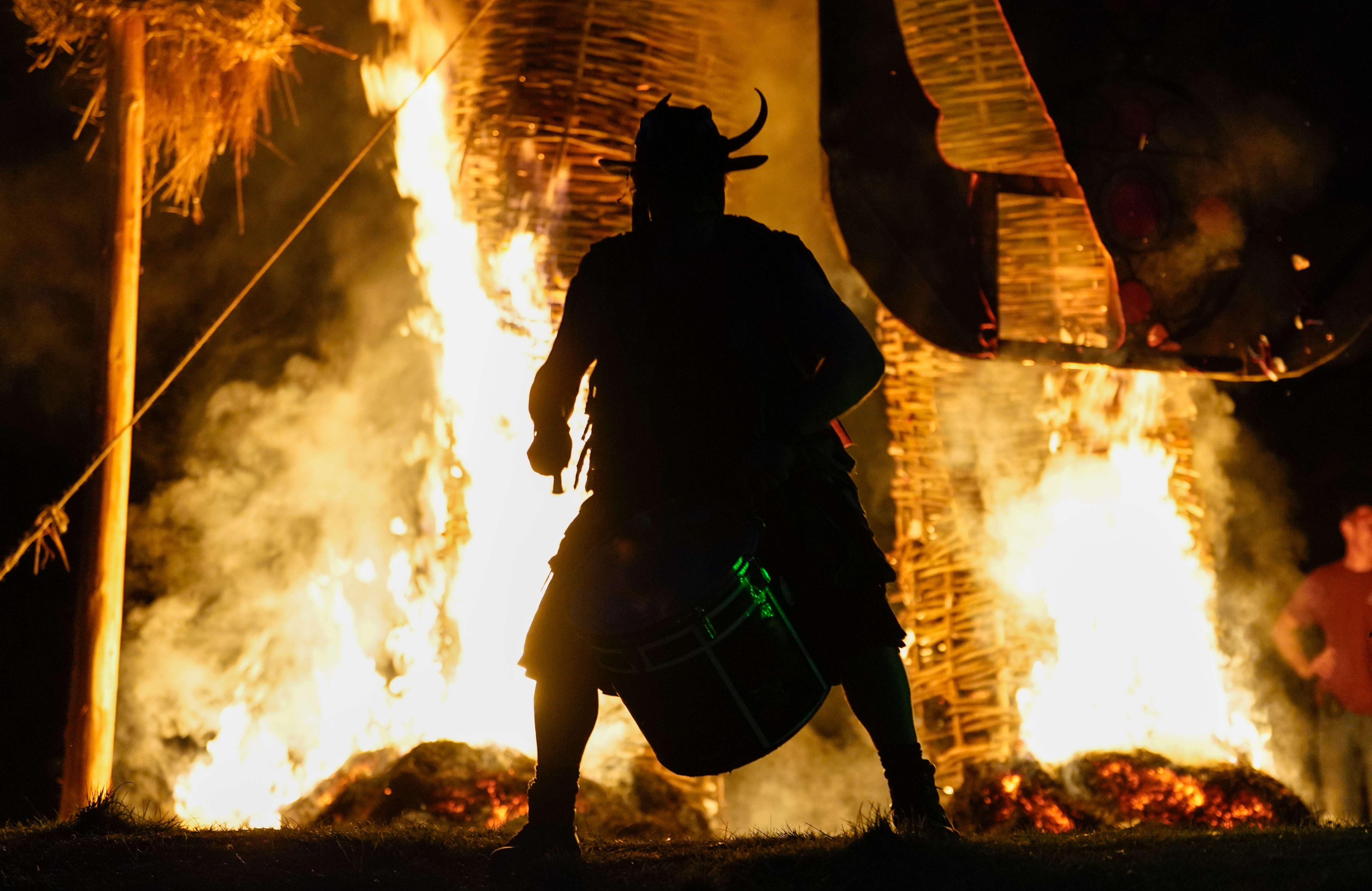 A member of the Pentacle Drummers performs in front of a burning wicker man during the Beltane Festival at Butser Ancient Farm, in Waterlooville, Hampshire (Andrew Matthews/PA)