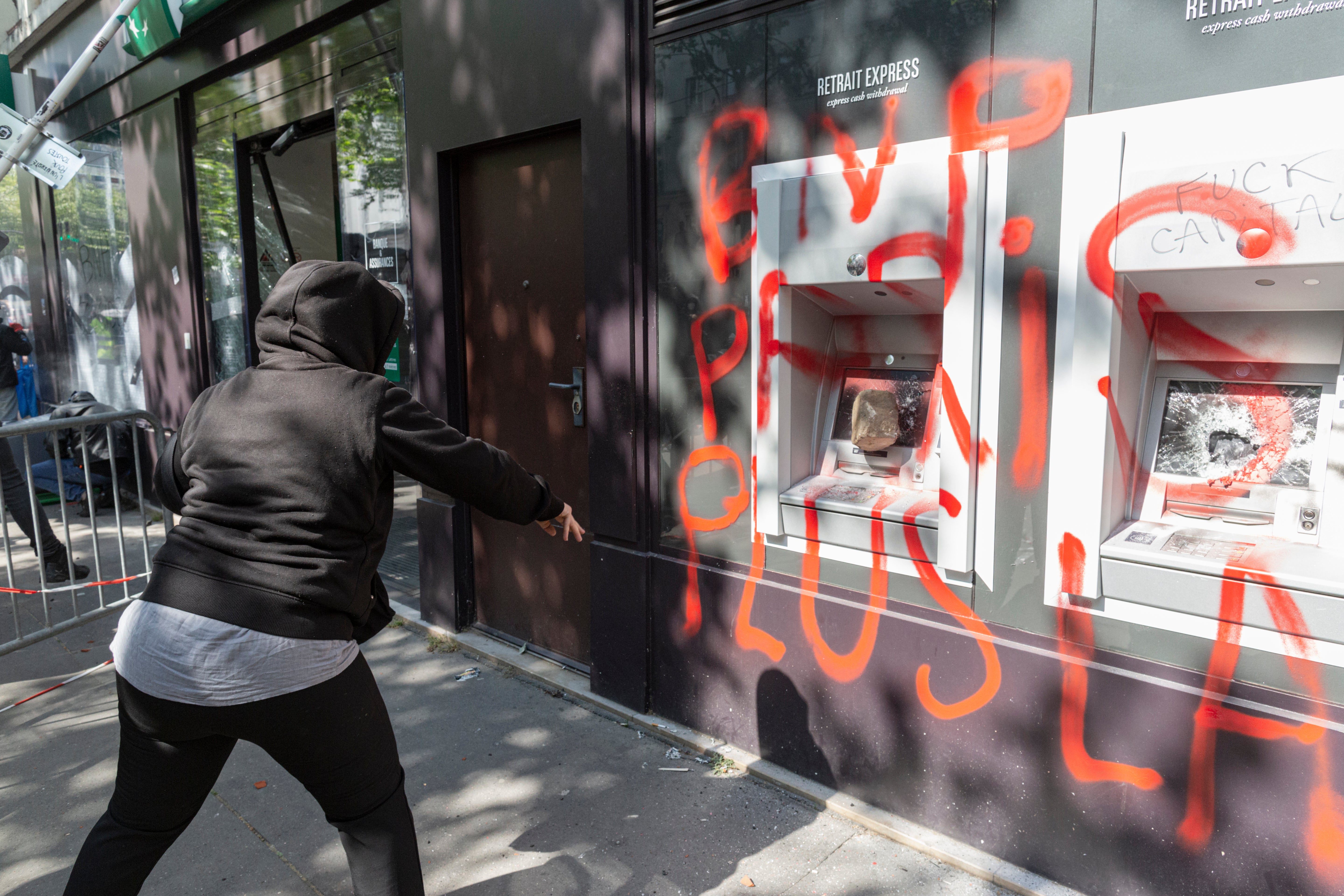 A demonstrator throws a rock at a cash machine outisde a bank that had been trashed by protesters in Paris