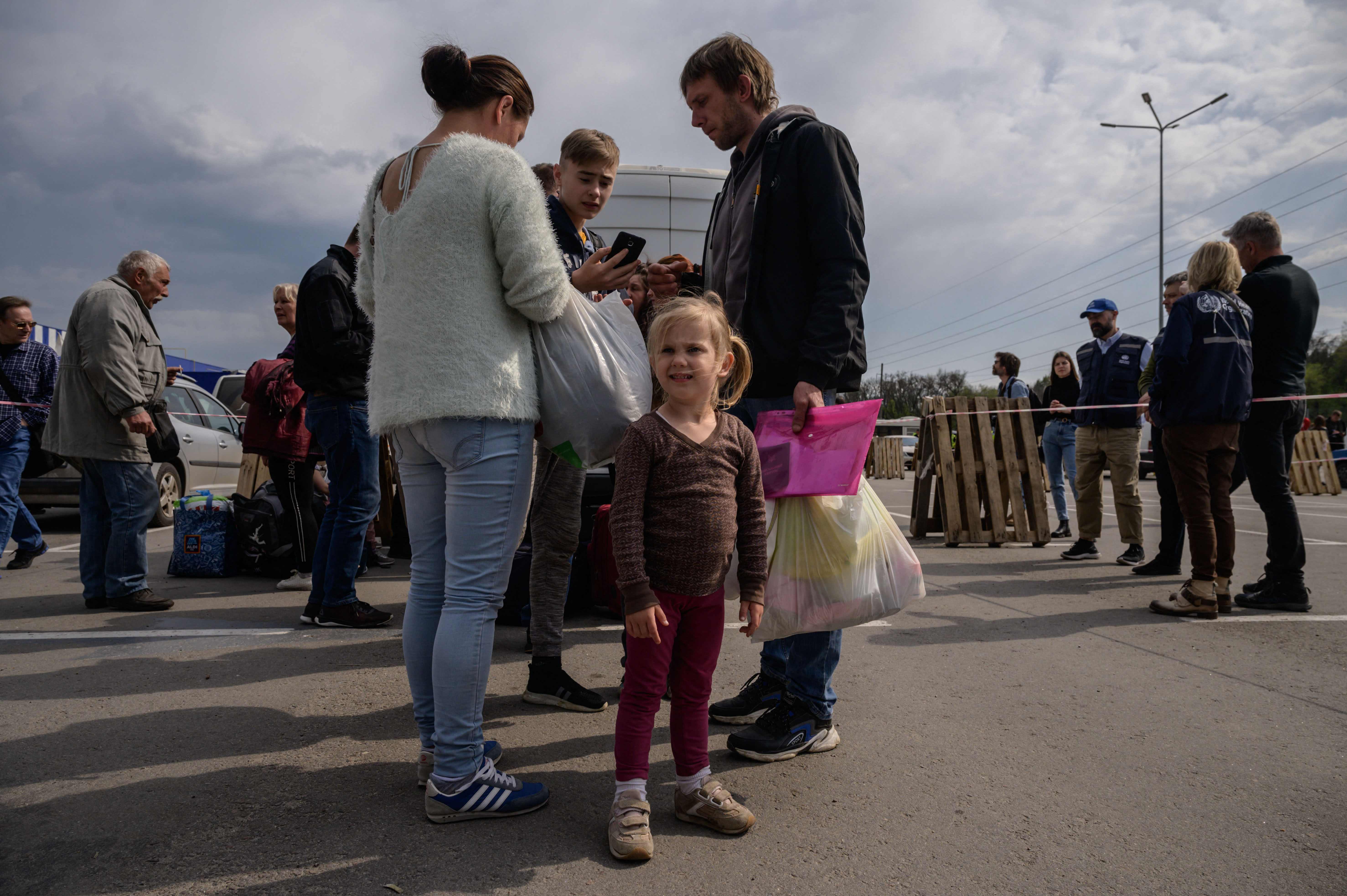 A family arrive from Russian-occupied Melitopol at a registration and processing area for internally displaced people in Zaporizhzhia ahead of an expected humanitarian convoy