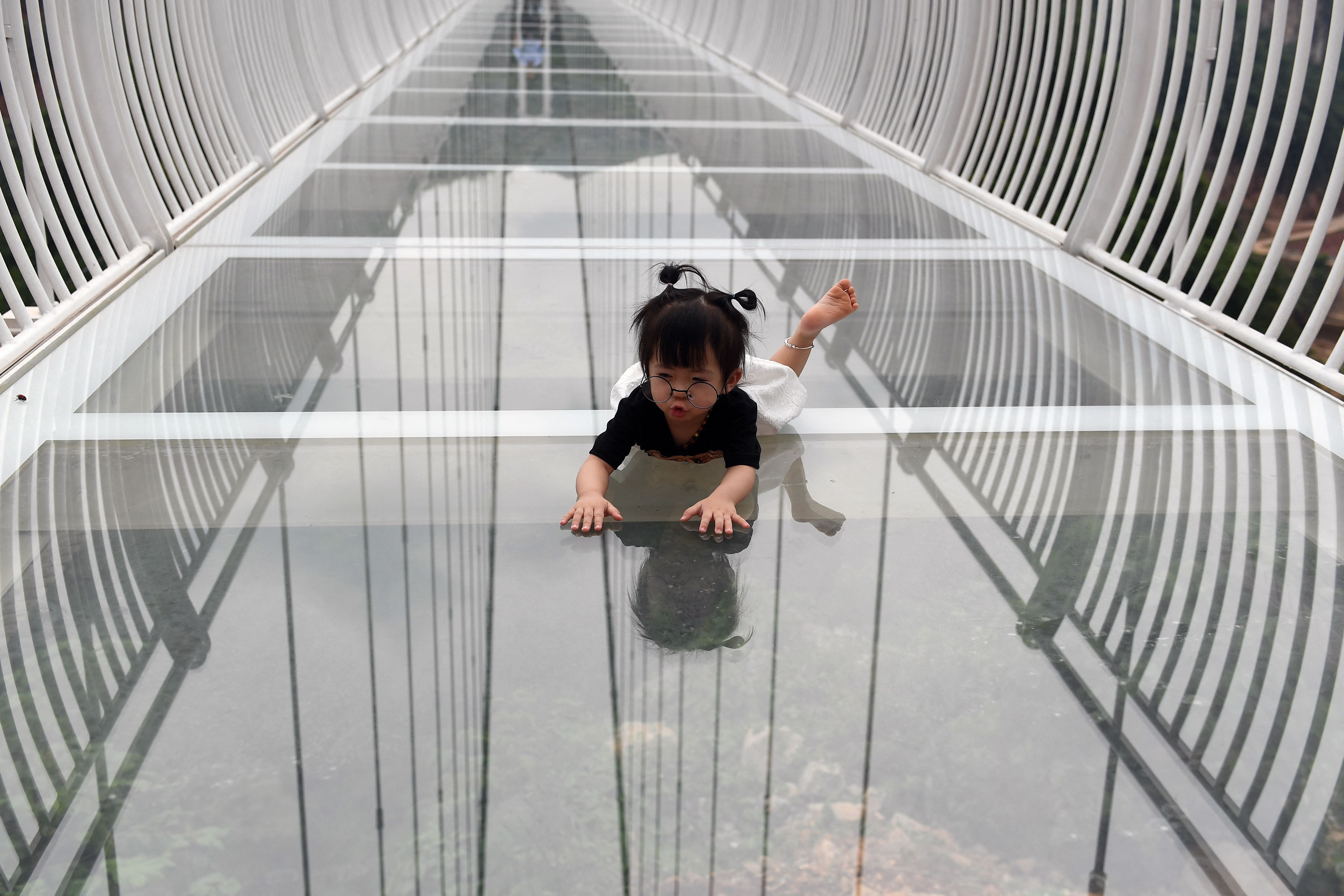 A young visitor crawls on the Bach Long glass bridge in Moc Chau district in Vietnam