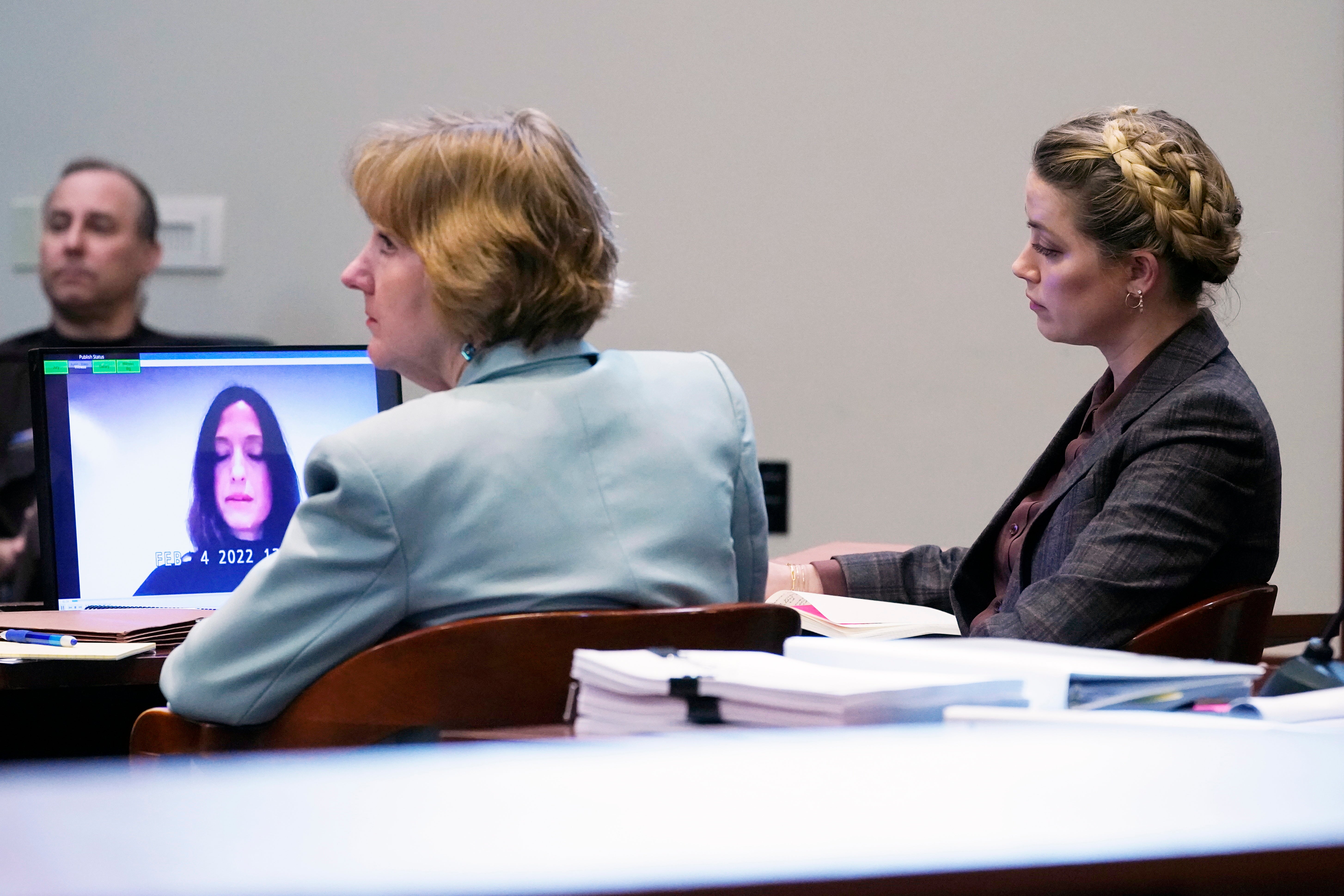 Amber Heard (R) and her attorney, Elaine Bredehoft, listen to Erin Falati, a former nurse of Heard, as she testifies remotely