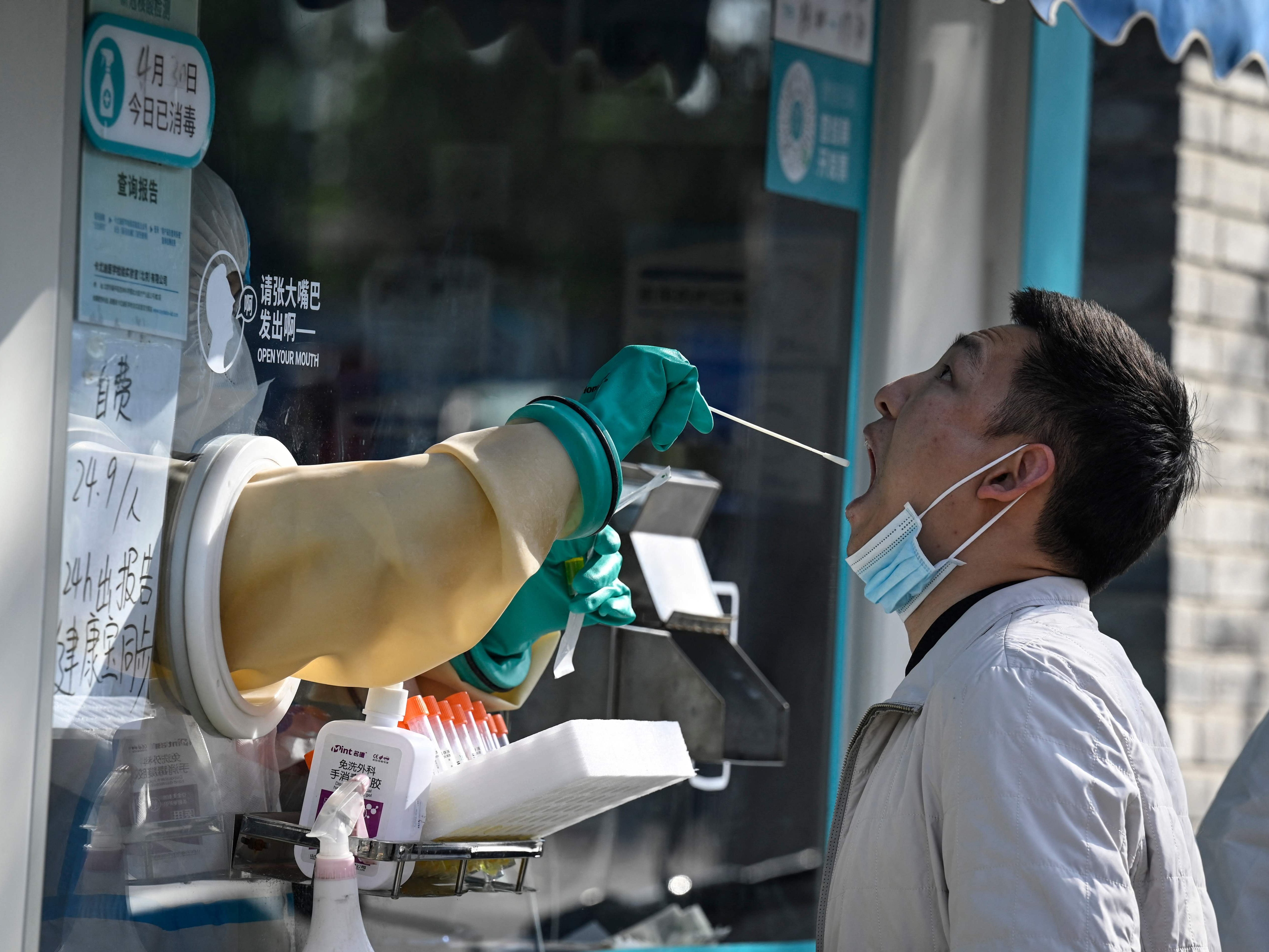 A health worker takes a swab sample from a man to be tested for Covid-19 coronavirus along a street in Beijing